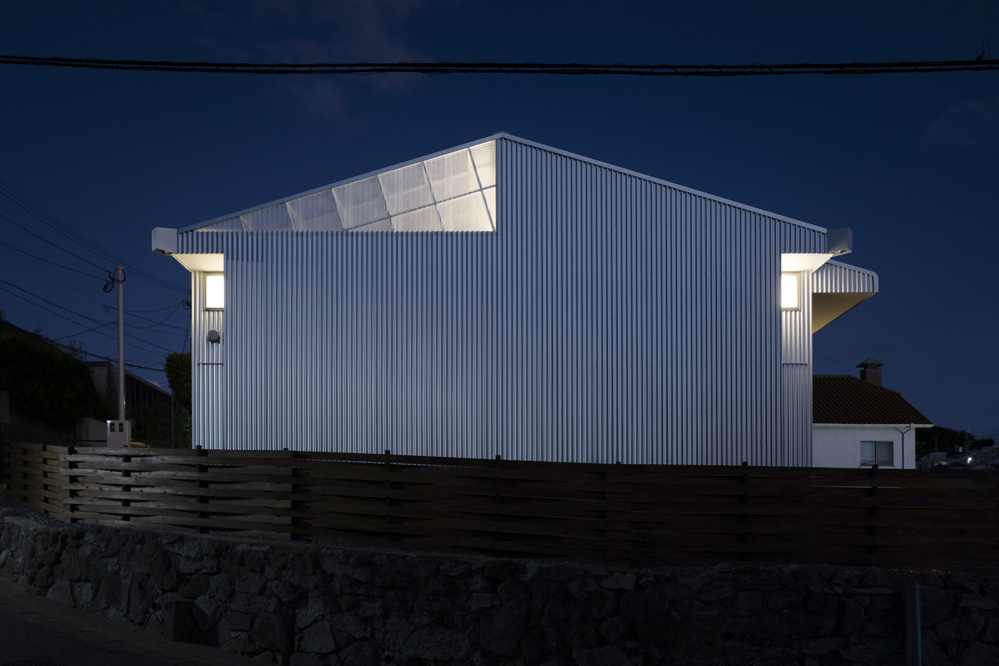 Rear elevation showing the angled roofline and projecting corner volumes at dusk
