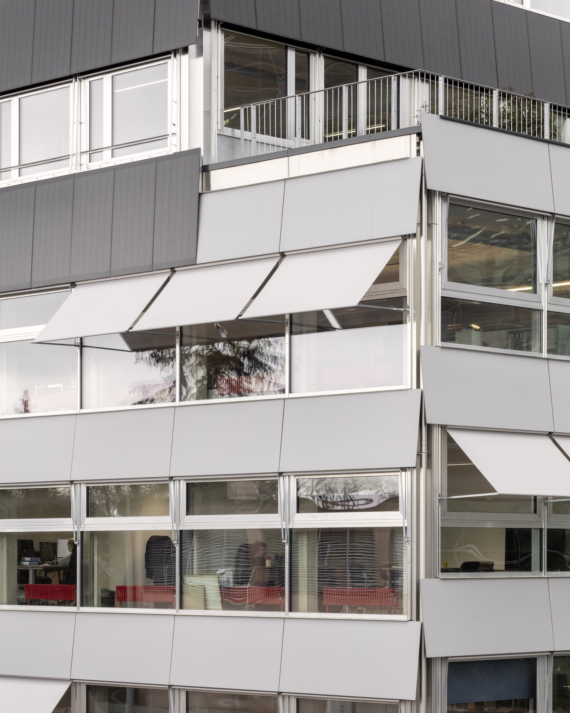 Facade detail showing staggered balconies with white awnings and horizontal window bands