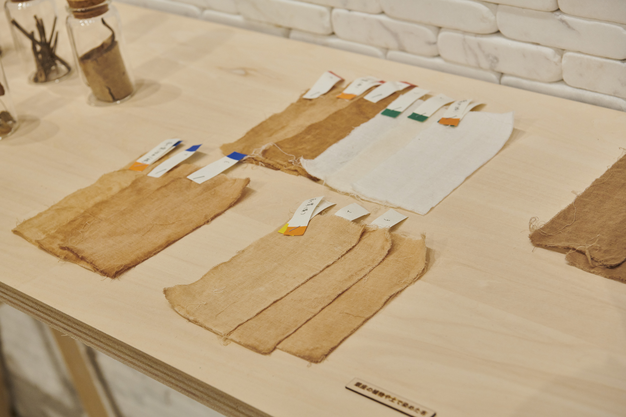 Plywood table displaying paper or textile samples with colored tabs arranged in rows