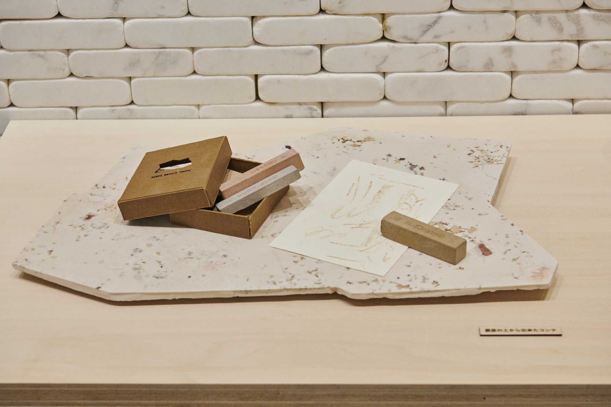 Timber stamp and printed sheet displayed on a terrazzo slab beside an open box with tools