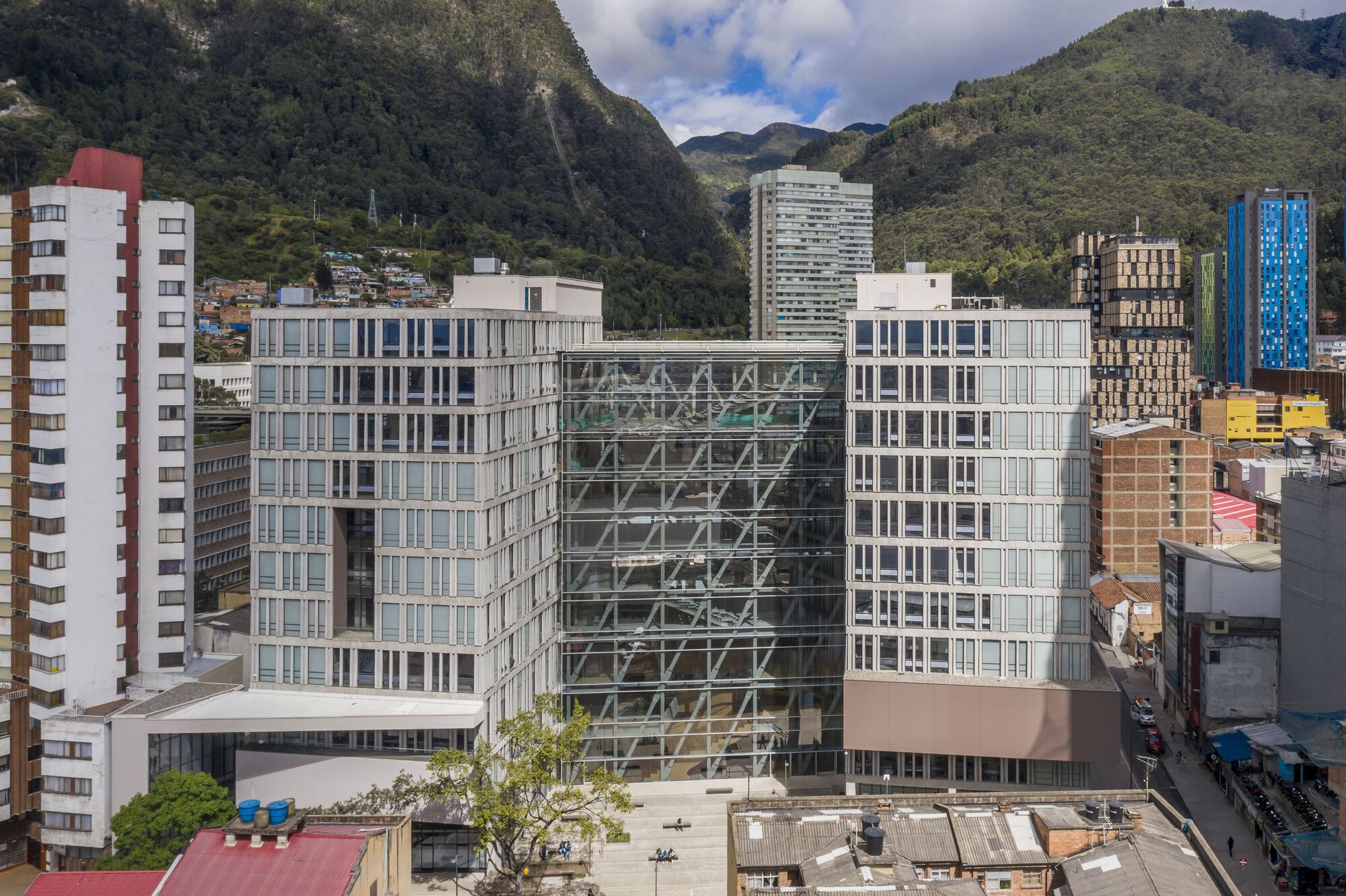 Elevated view of the glass office blocks flanking a central diagrid tower core with green mountains beyond