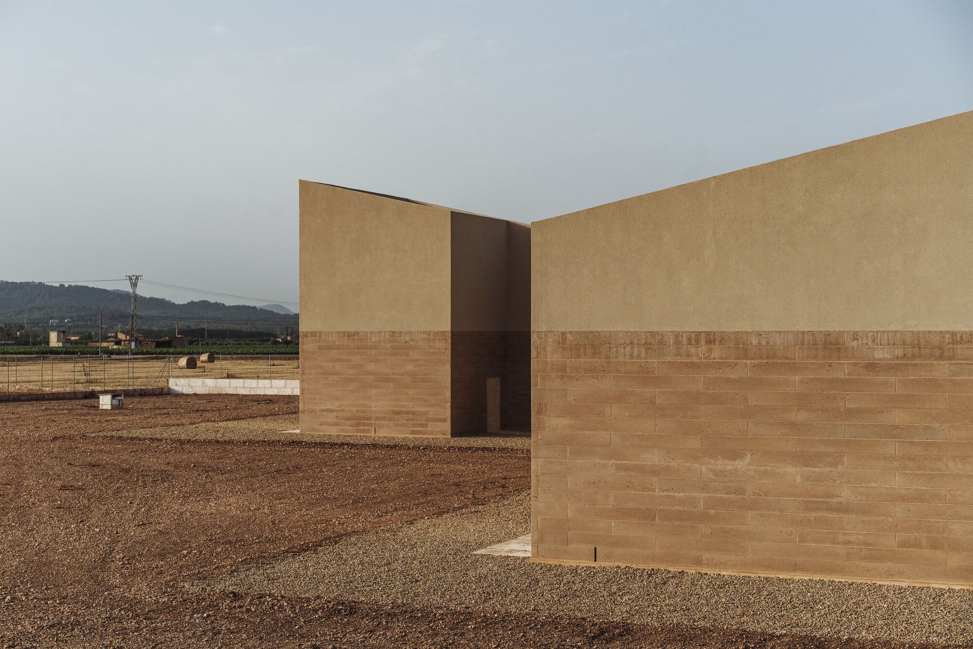 Corner detail of the two-tone facade with rammed earth base and stucco upper volume