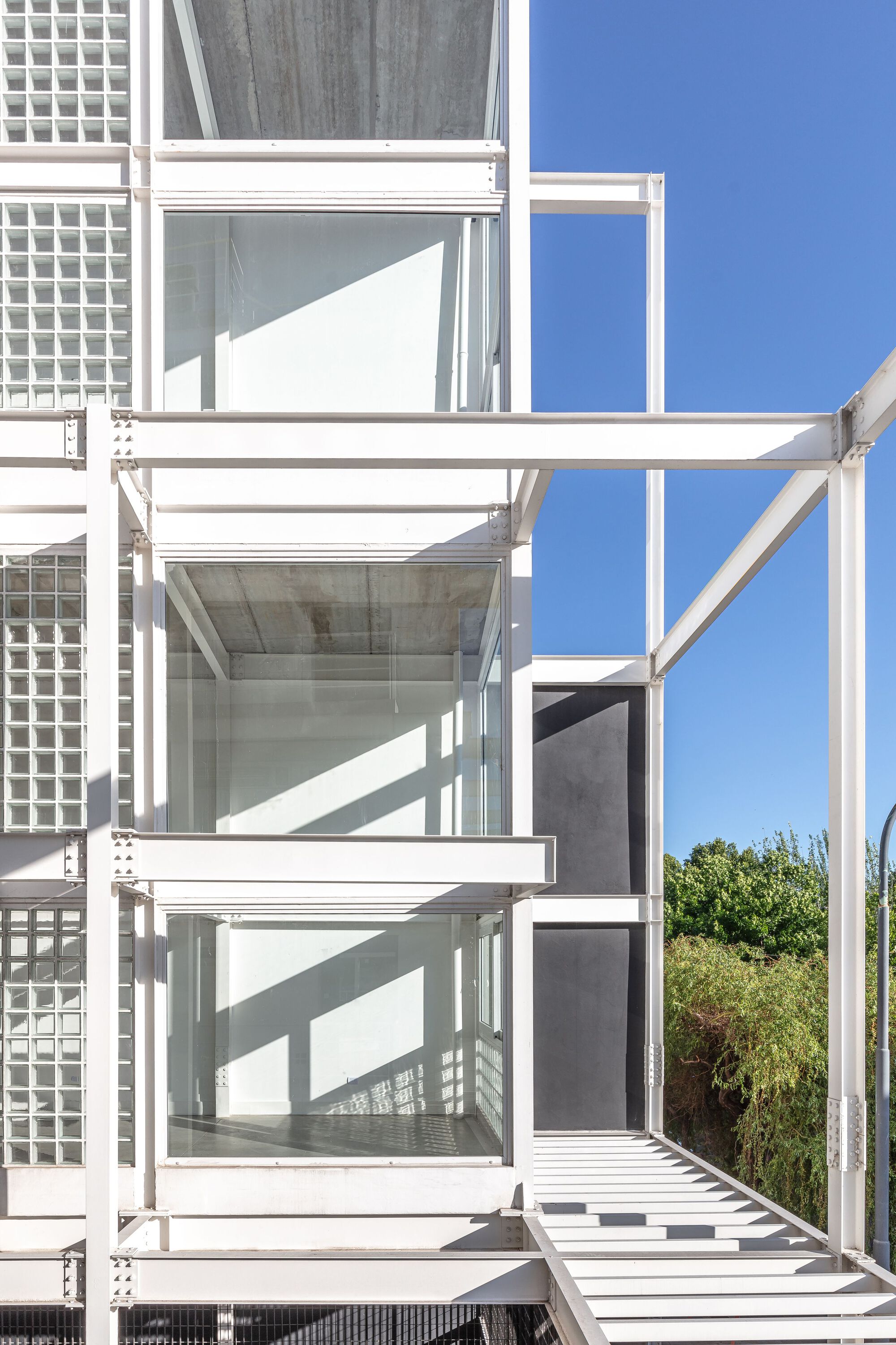 Exterior white steel balconies and glass block facade under clear blue sky