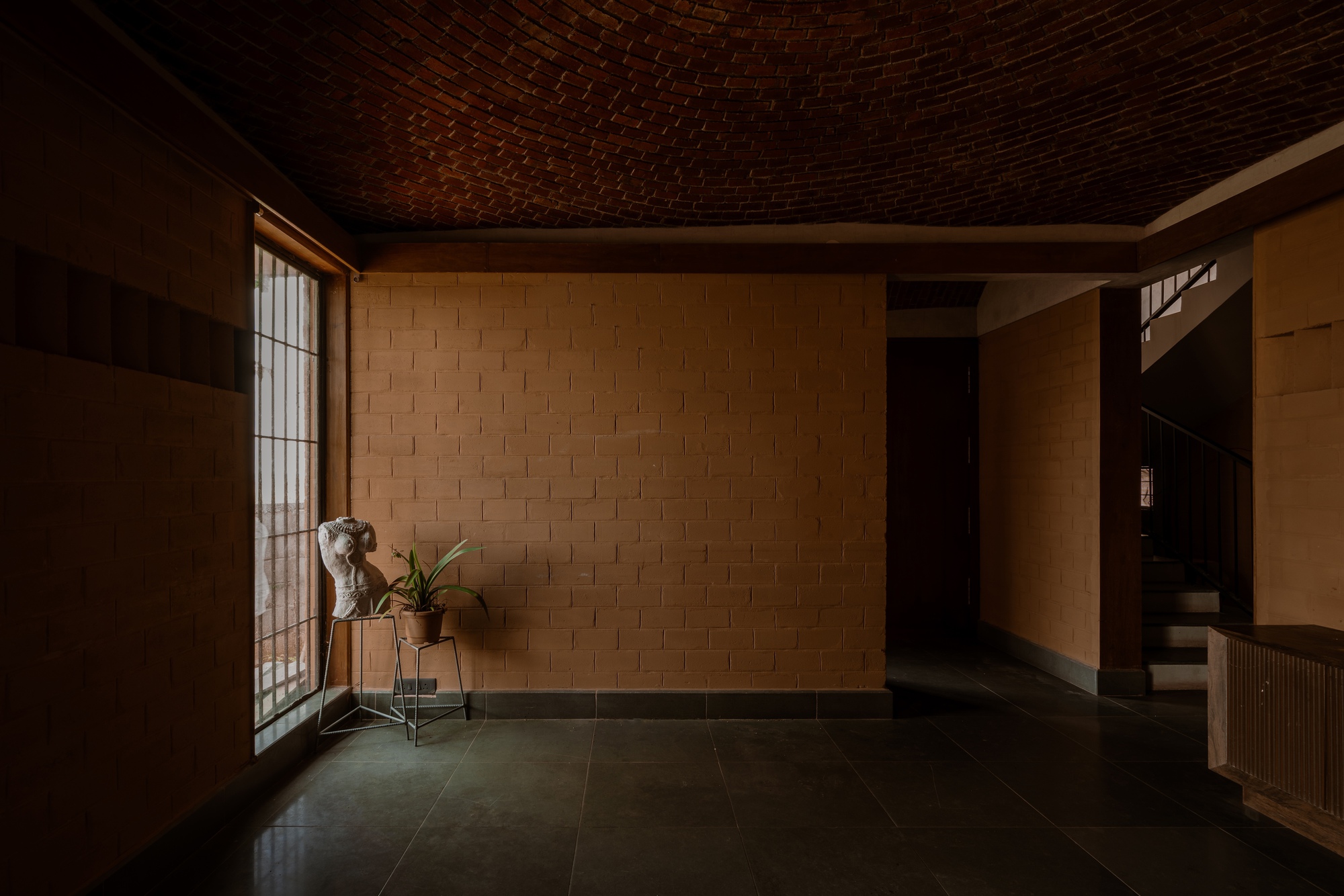 Entry hall with basket-weave brick vaulted ceiling and woven block walls in soft afternoon light