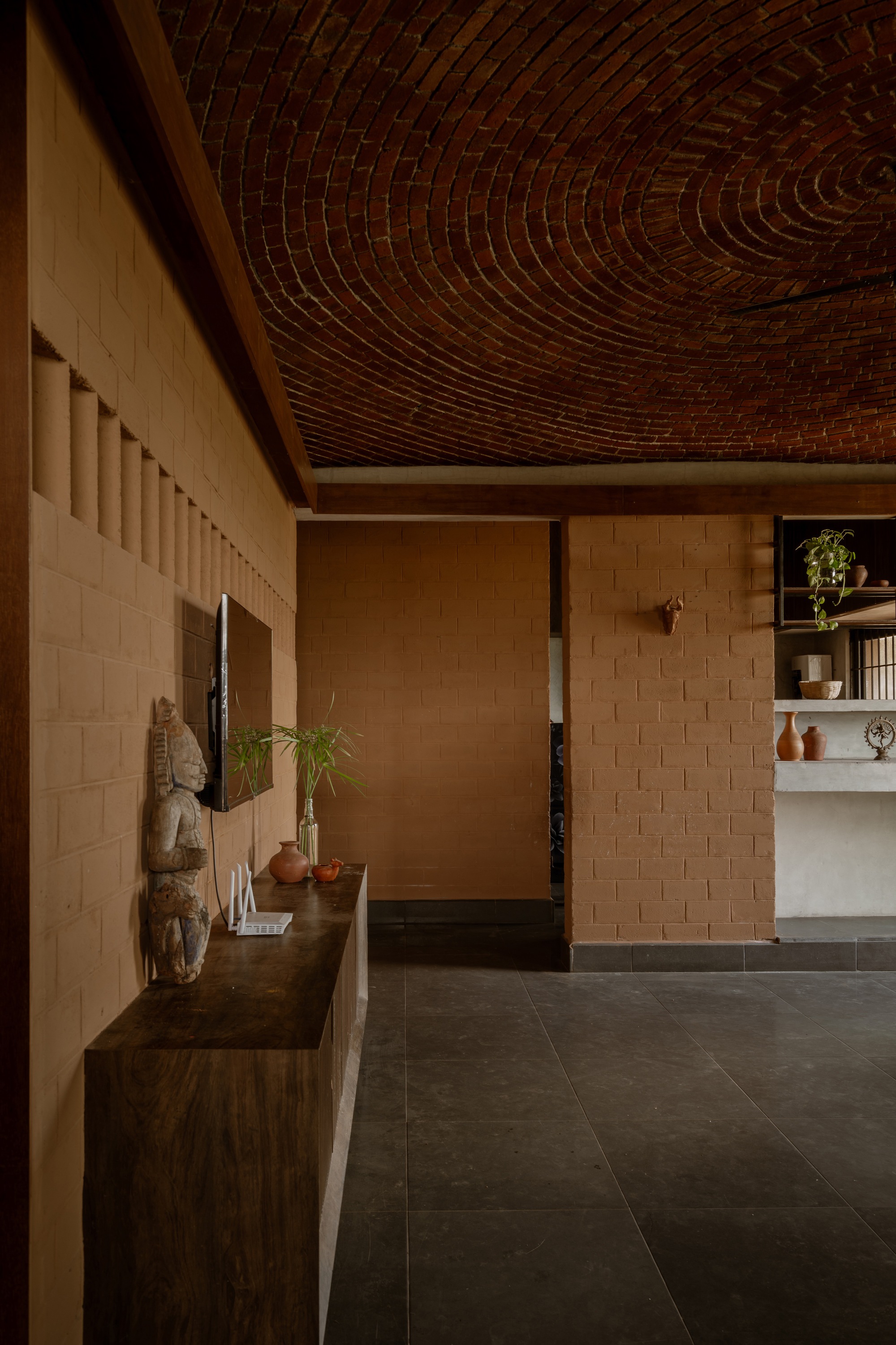 Interior passage with carved brick barrel vault ceiling and wooden bench along block textured wall