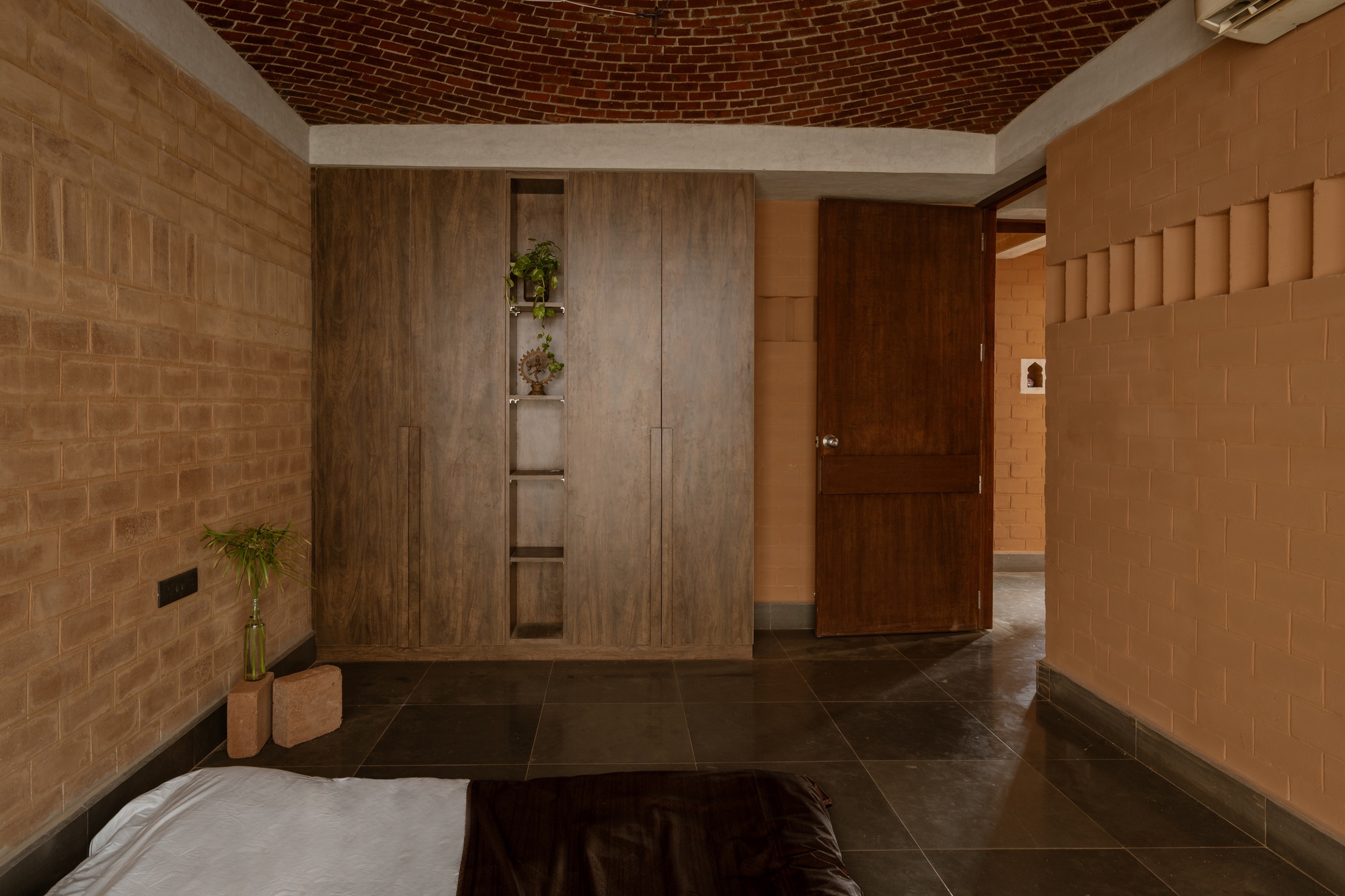 Entry foyer with timber door and wardrobe beneath a curved brick vault and corner planters