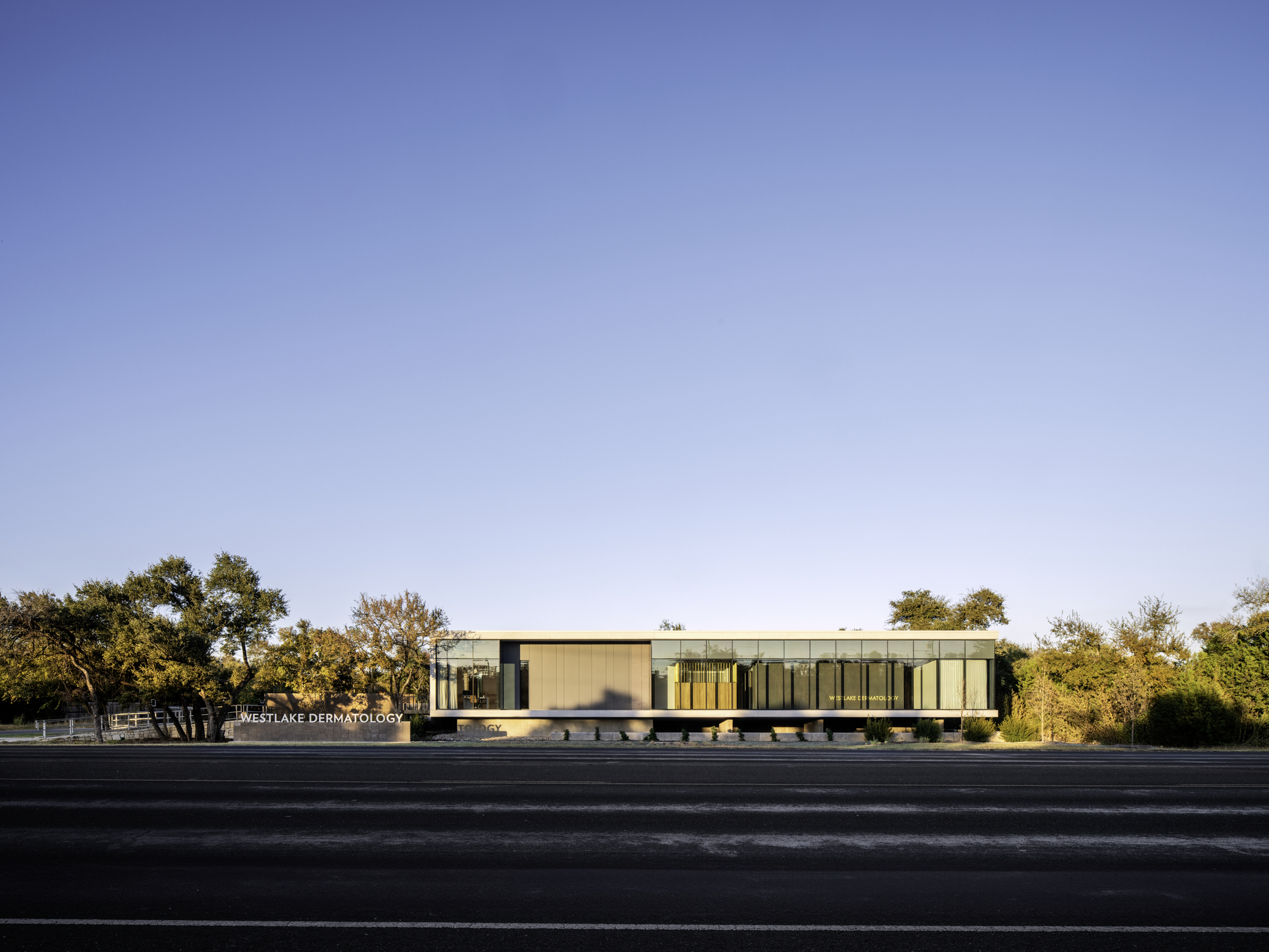 Long view of the elevated horizontal volume spanning above a landscaped base with native trees