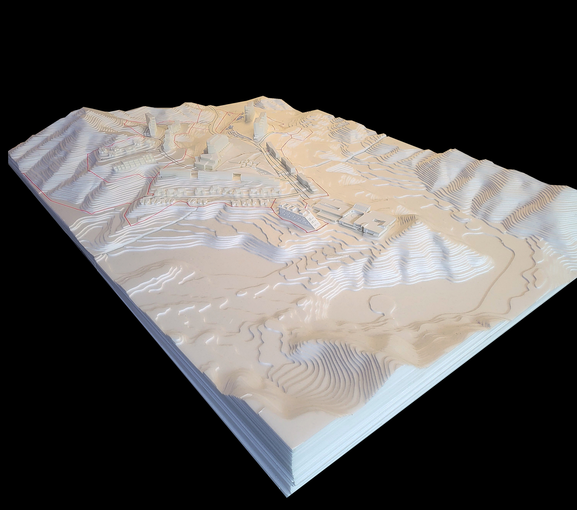 The image shows a detailed architectural model of a site plan, emphasizing the topography and landscape. The model is constructed in layers, revealing contour l