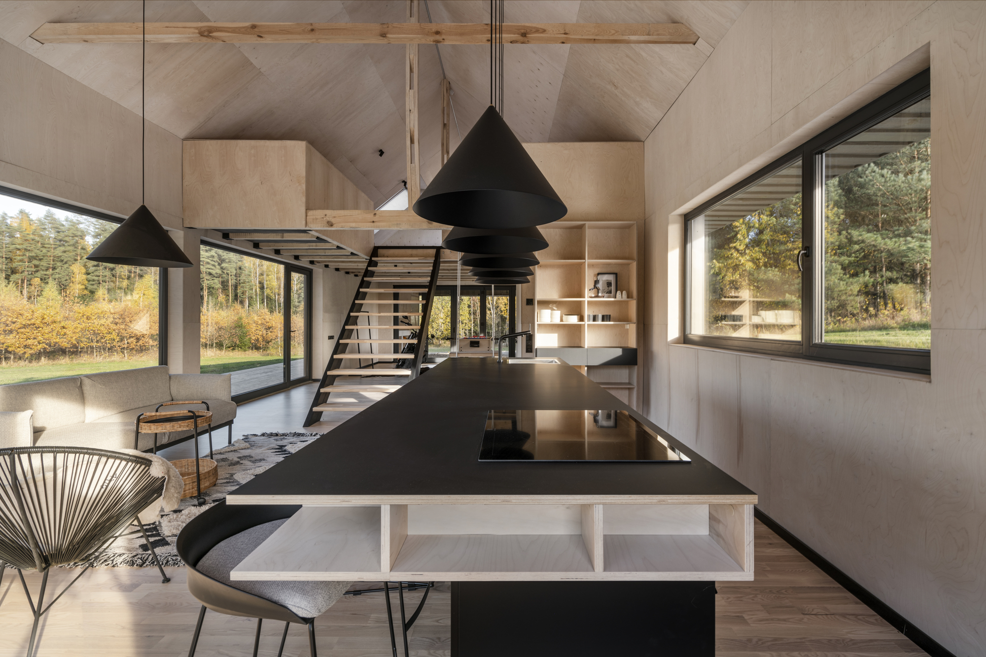 Open kitchen with black island beneath conical pendant lights and plywood vaulted ceiling