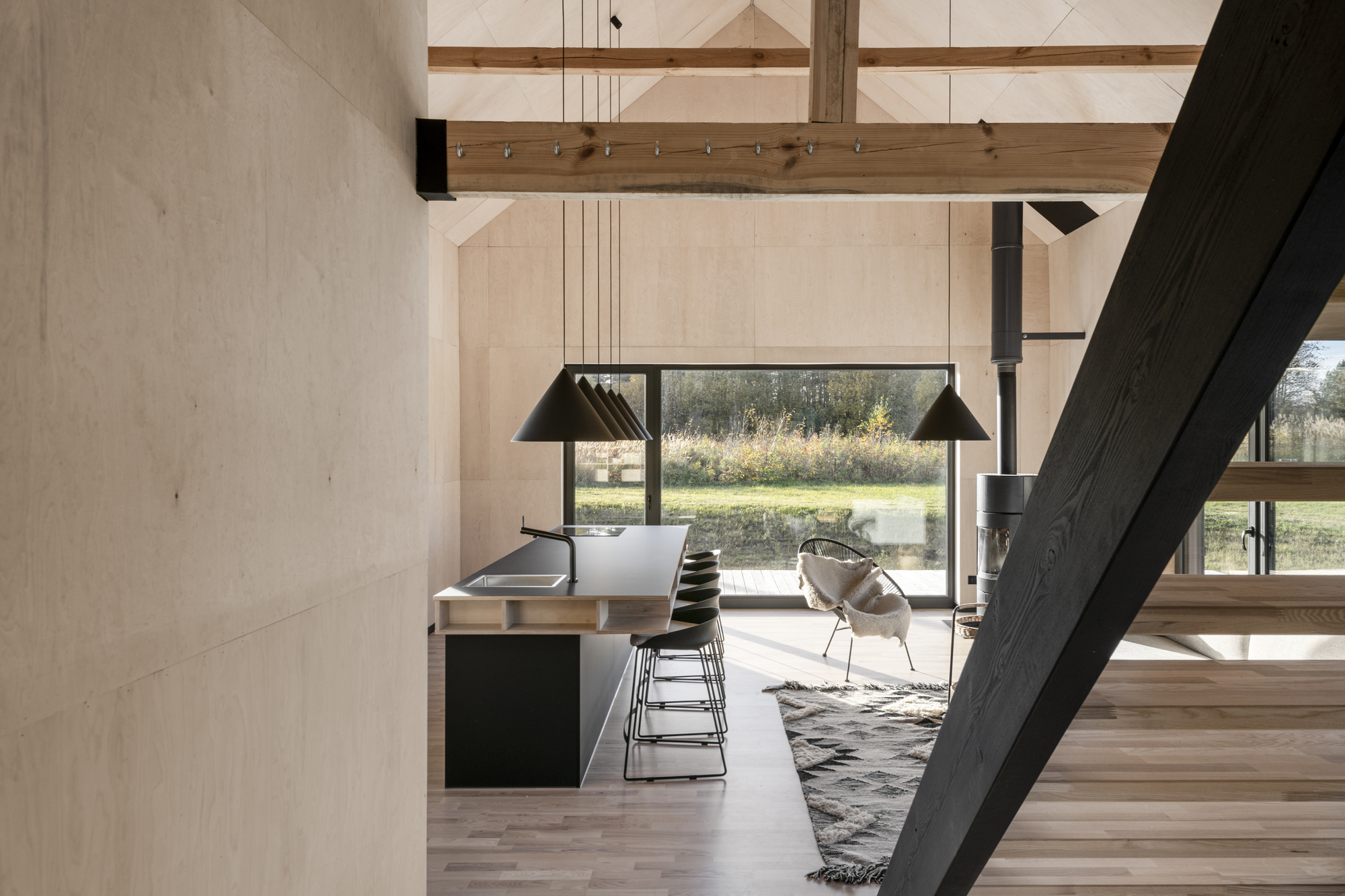 Interior view showing exposed timber beams and black steel stair alongside kitchen island