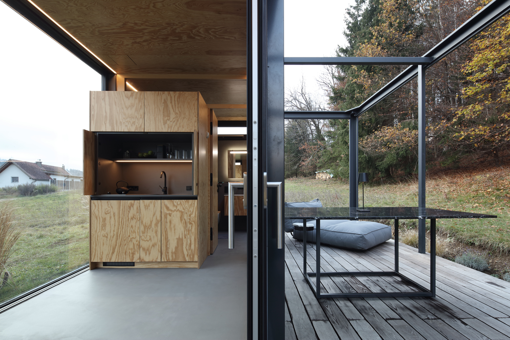 Interior view from the kitchenette looking out through open glass walls to the timber deck