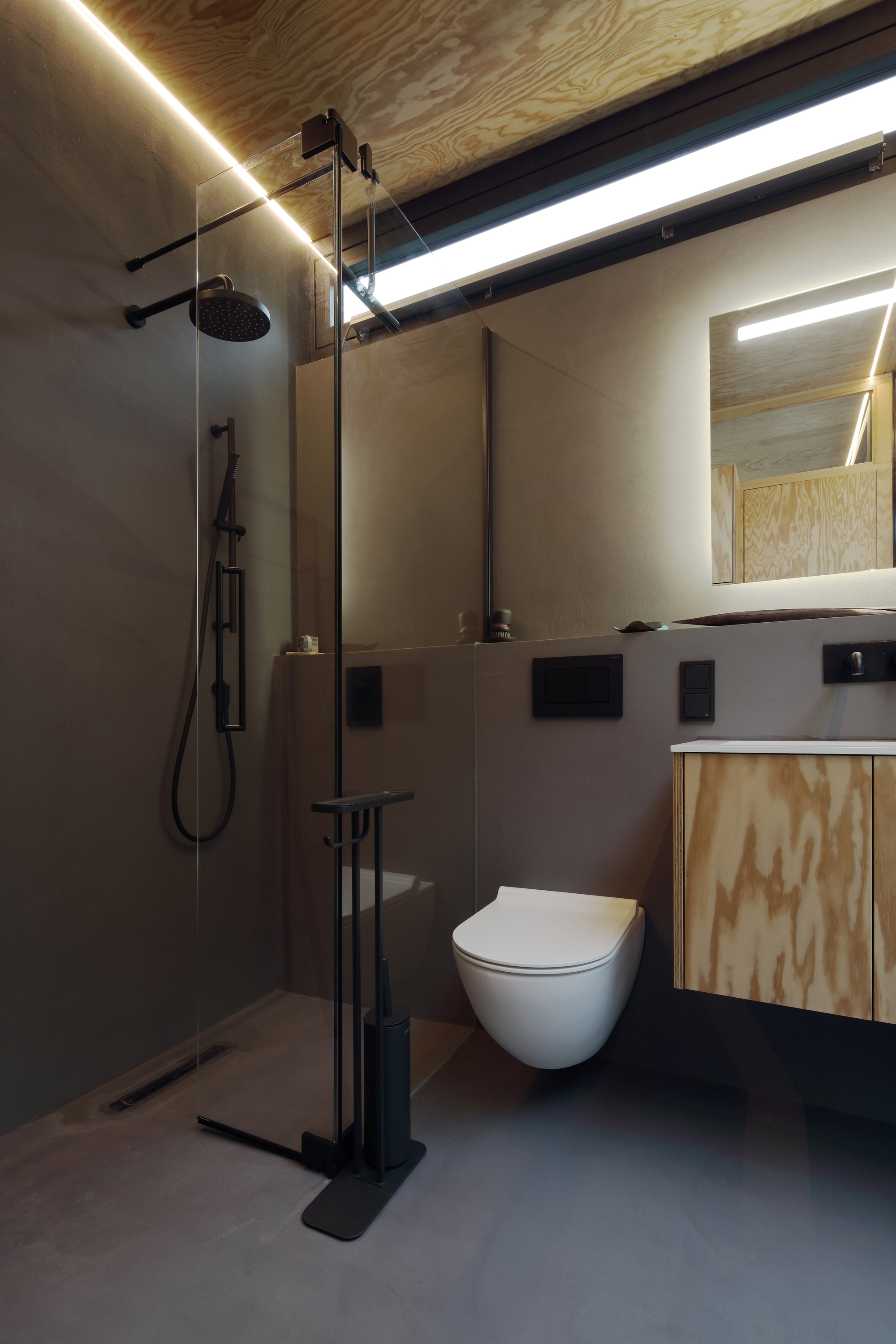 Bathroom interior with wall-mounted toilet, plywood cabinetry and linear lighting in the ceiling