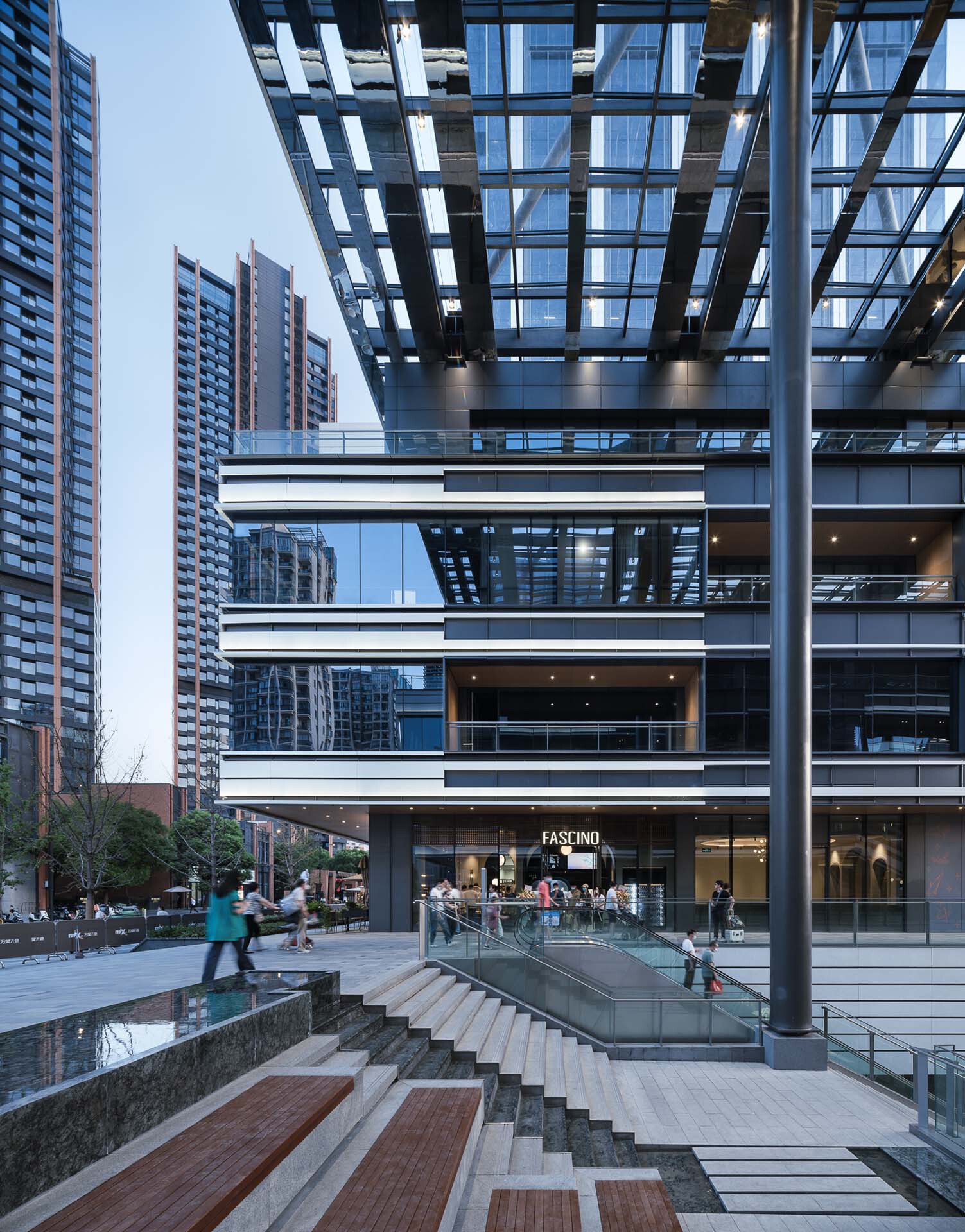 Sunken plaza with stone steps and water feature beneath the steel frame canopy at twilight