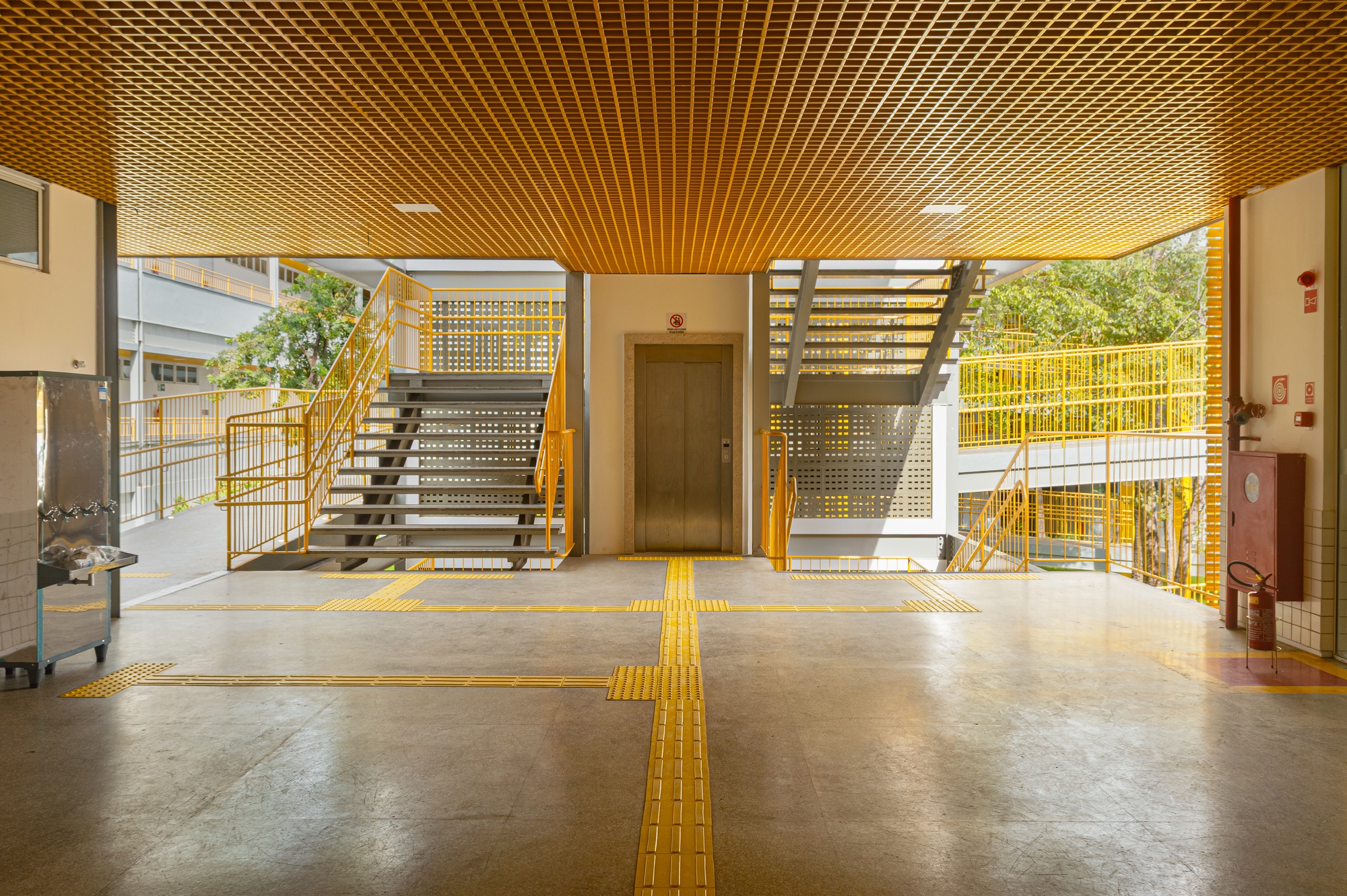Lobby with yellow tactile pavement strips crossing polished concrete floor beneath slatted timber ceiling
