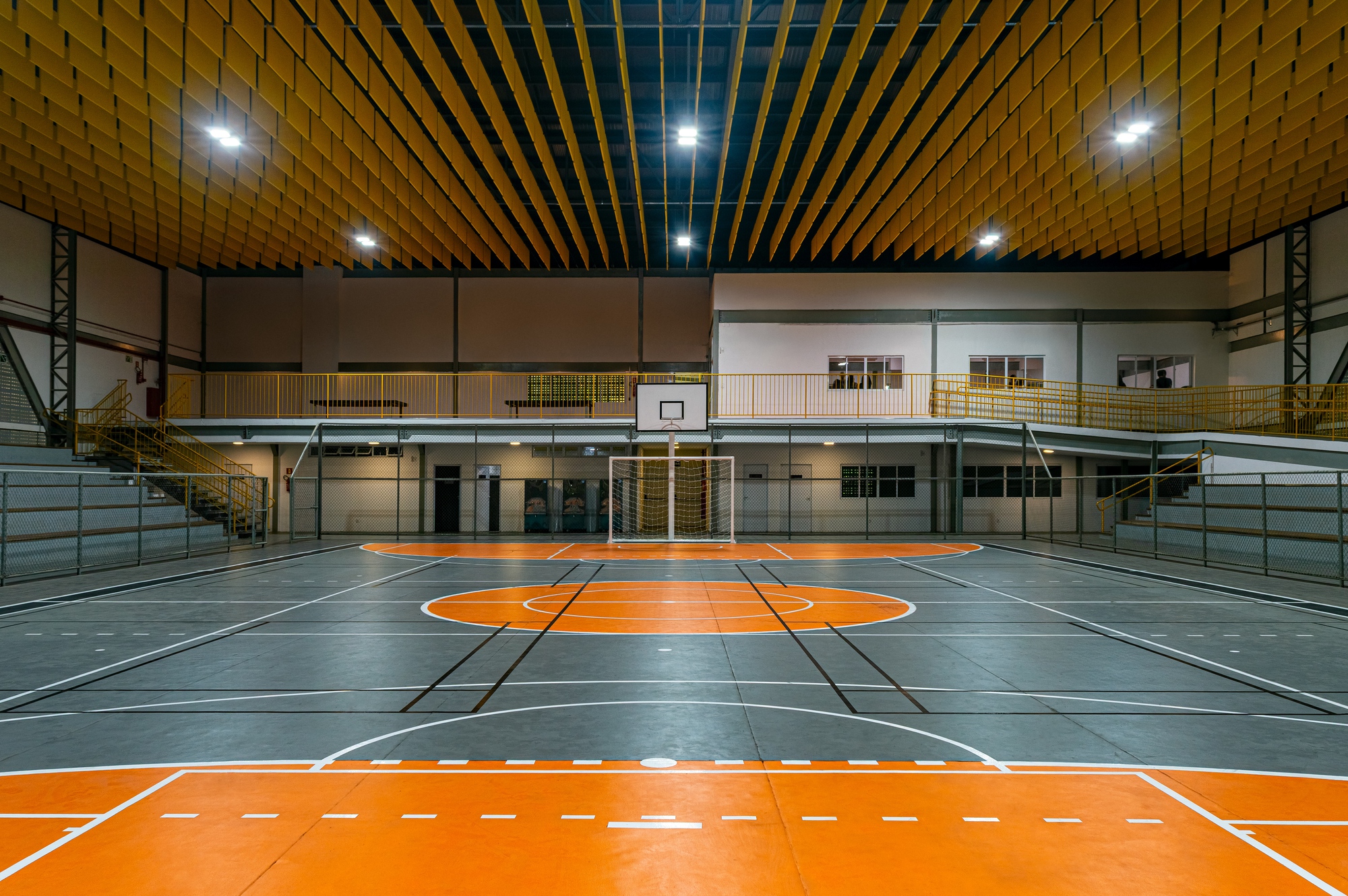 Indoor sports court with orange markings on grey flooring beneath a slatted timber ceiling