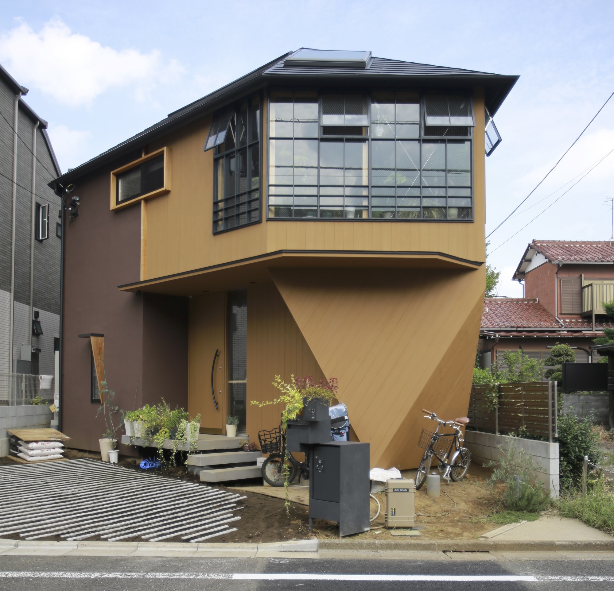 Street view of the cantilevered upper volume with gridded windows and ochre plaster facades