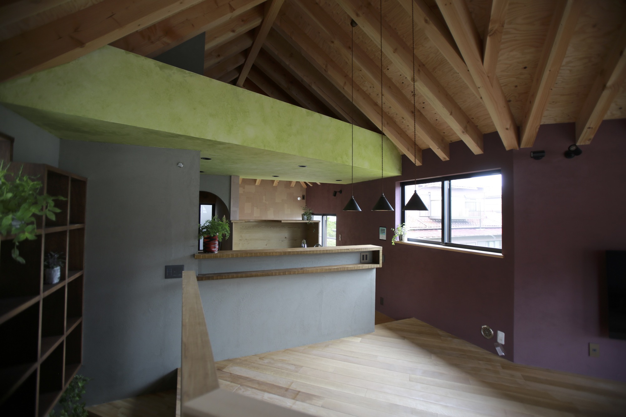 Open plan space with exposed timber rafters connecting kitchen and living area under daylight