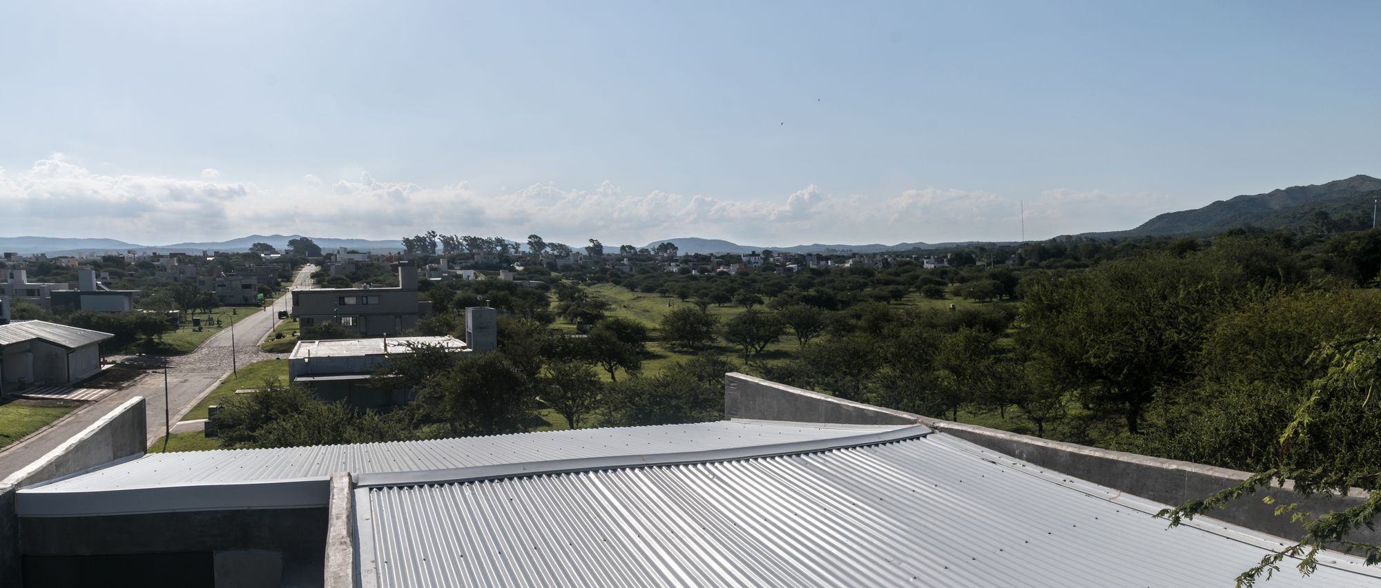 Corrugated metal roof planes extending over the suburban landscape with mountains in distance