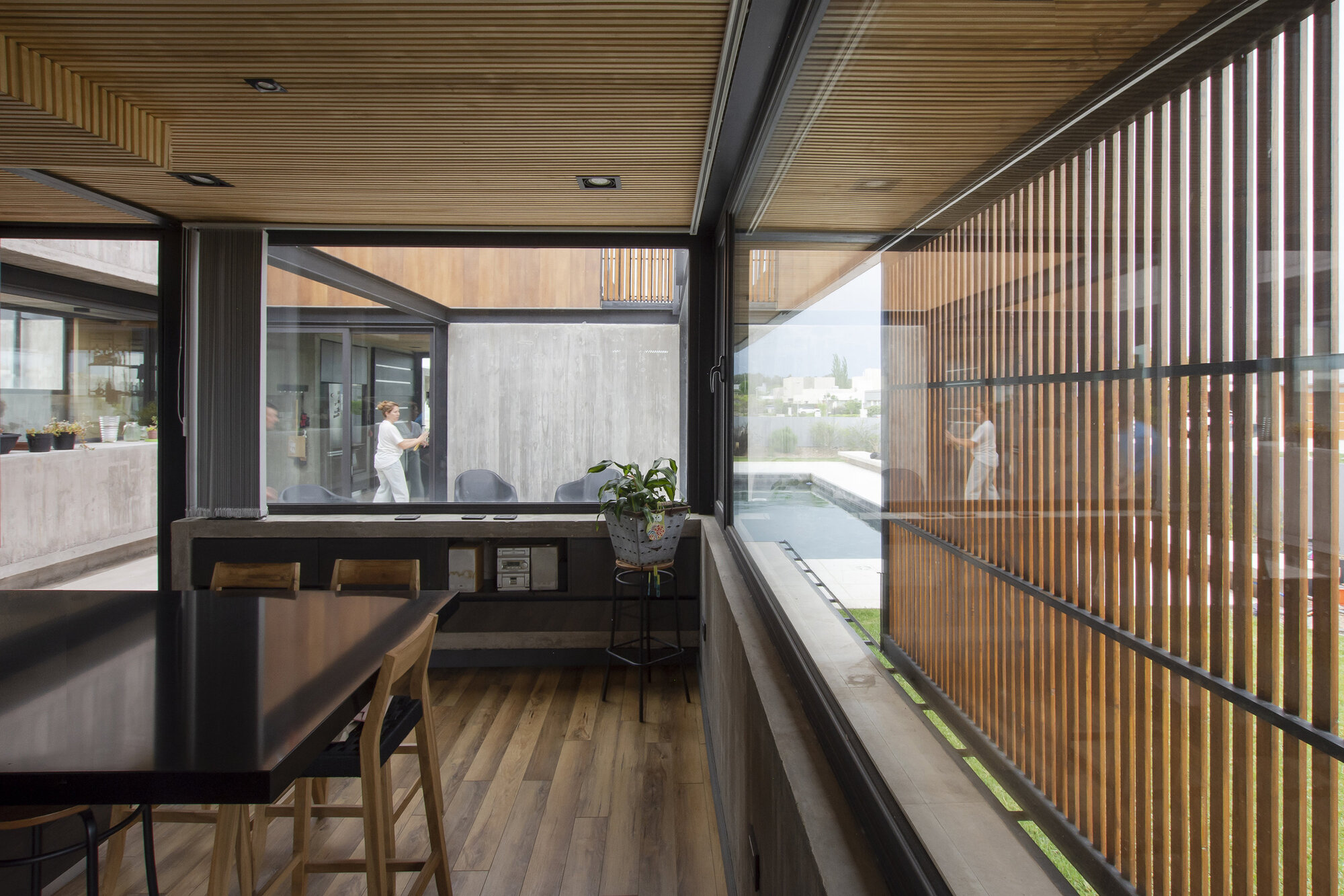 Interior dining area with vertical timber slat screens and a slatted wood ceiling under natural light