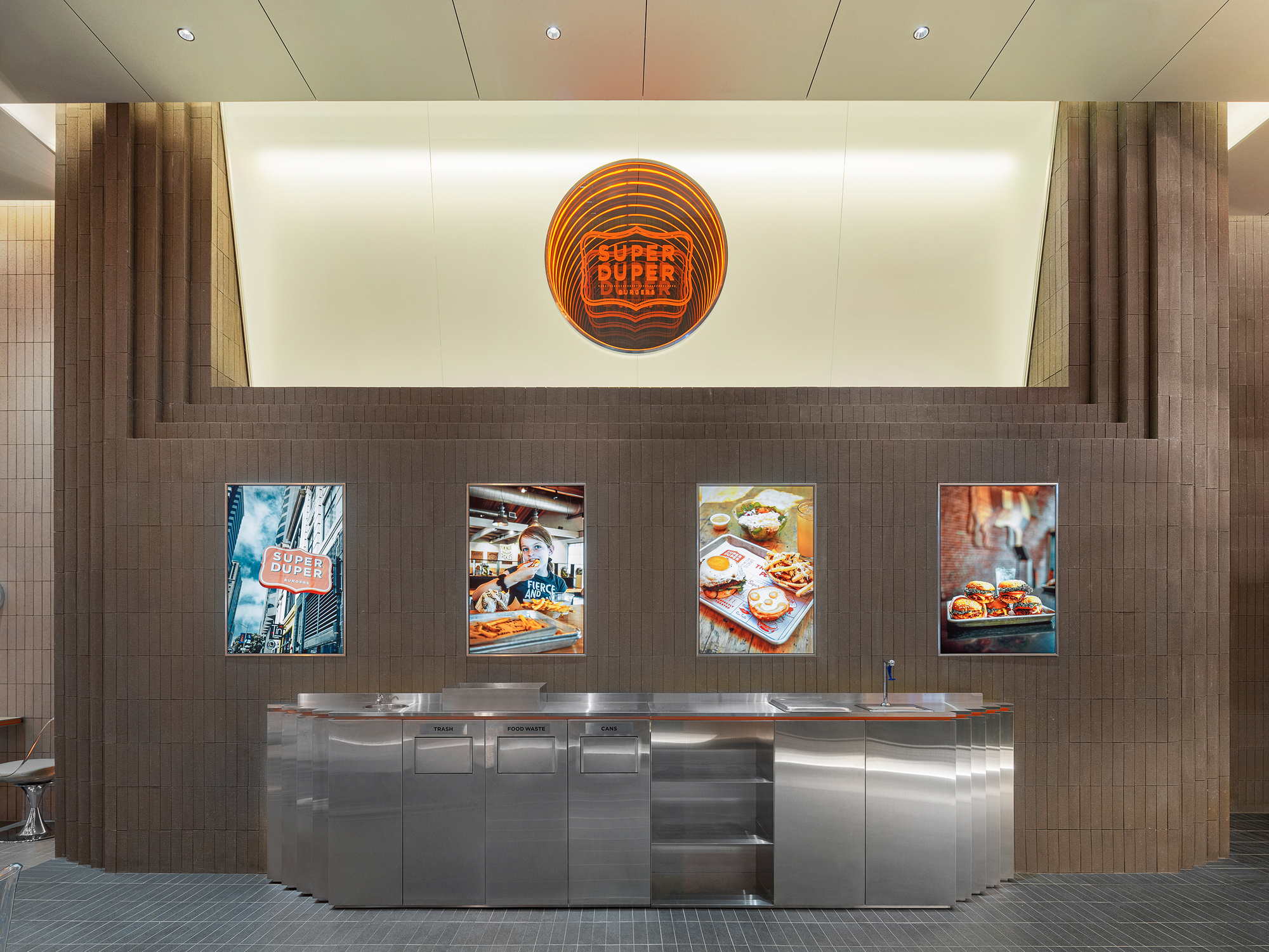Service counter with stainless steel base and backlit wall displaying four framed food photographs