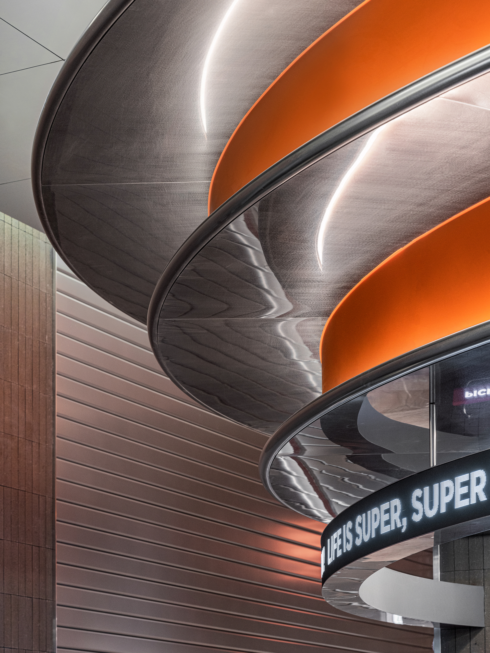 Close-up of layered curved ceiling baffles with orange bands and edge-lit perimeters