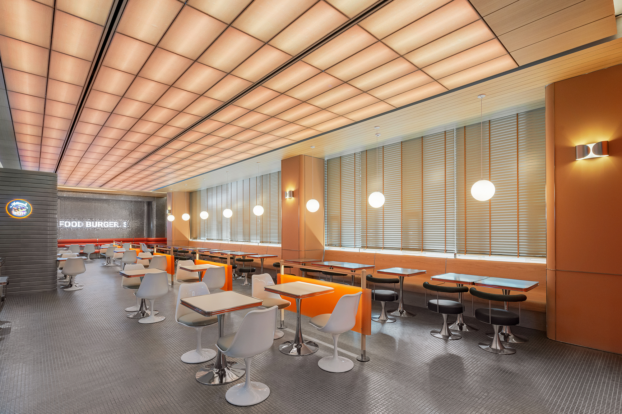 Long dining room with vertical slatted blinds along window wall and sphere pendant lights overhead