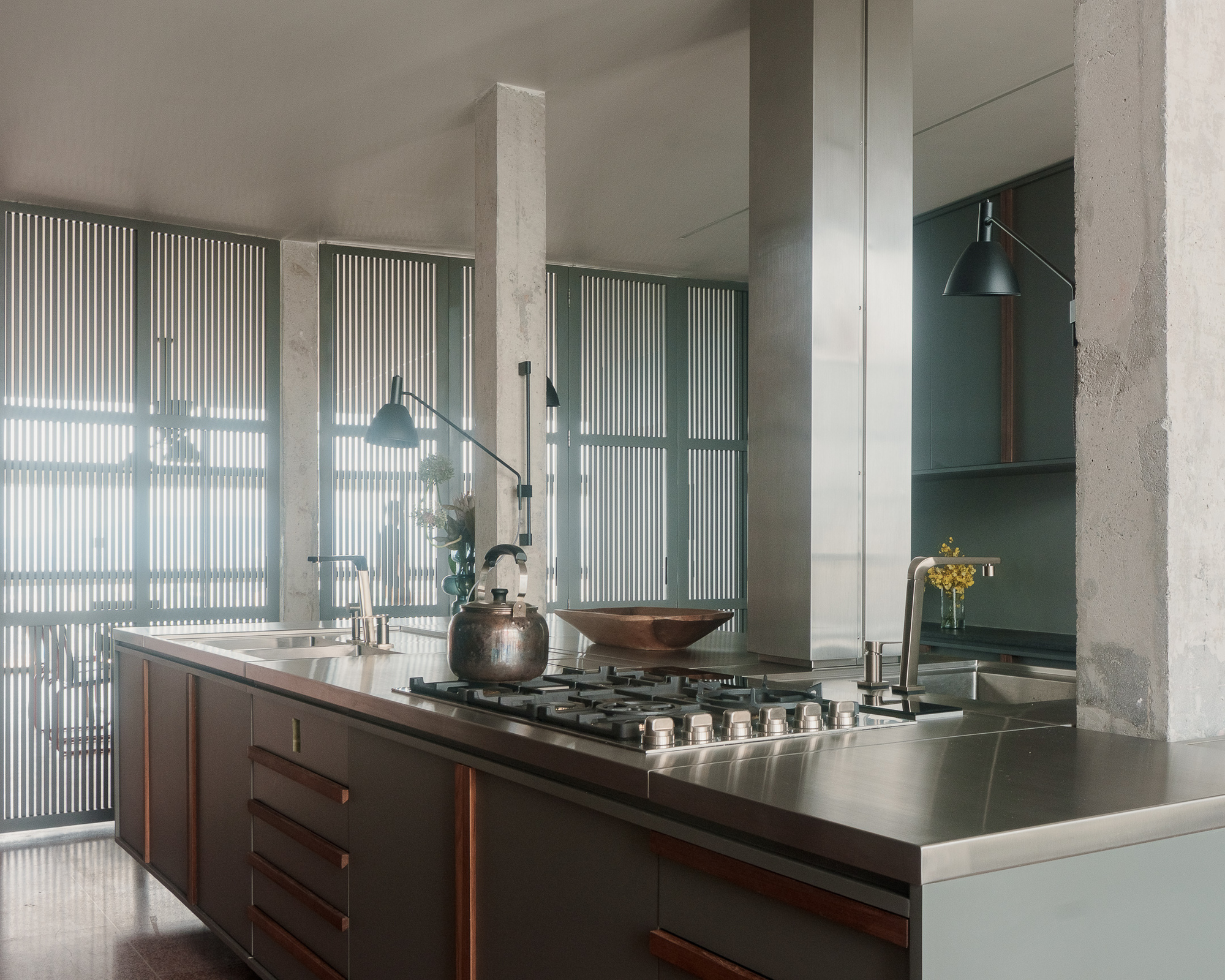 Island counter with gas cooktop framed by concrete columns and vertical fluted glass panels
