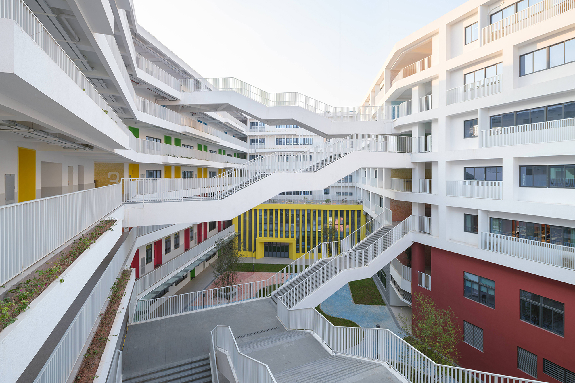 Central courtyard with intersecting white pedestrian bridges and coloured wall panels under a pale sky