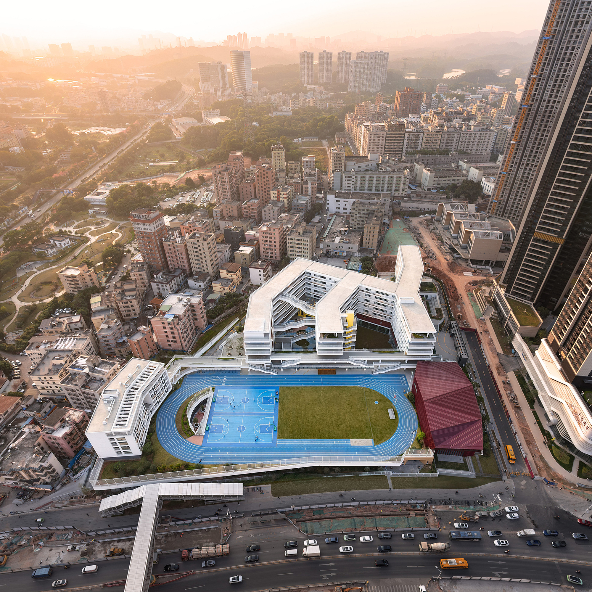 Aerial view of the white terraced building with rooftop sports track and field at sunrise