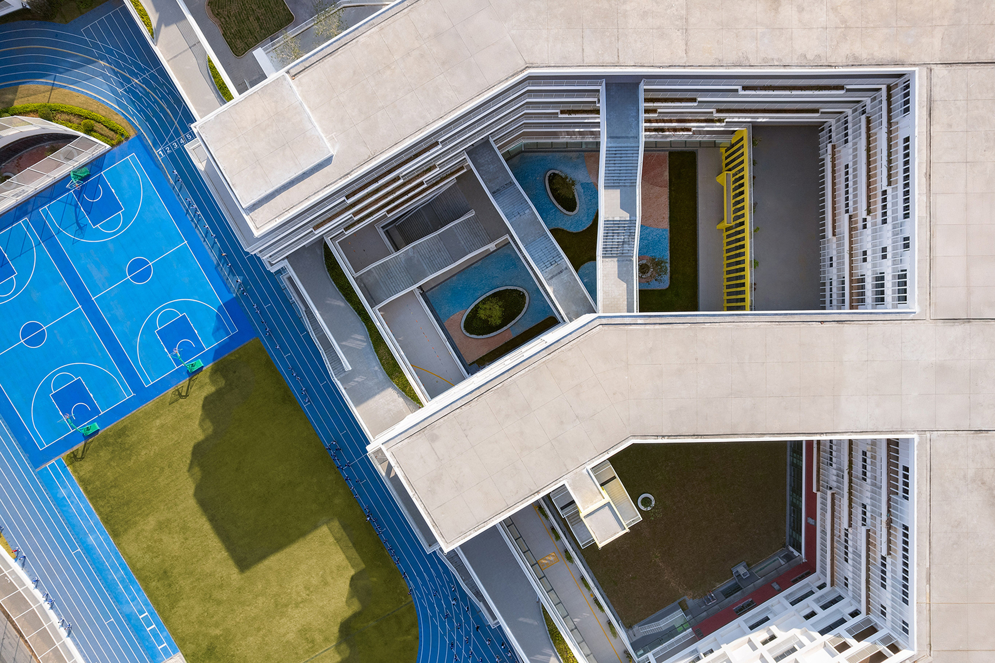 Top-down view of layered concrete courtyards with circular planters between stepped building volumes