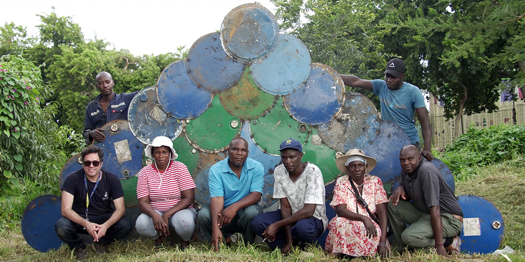 Group portrait in front of a weathered painted metal panel with circular and arched motifs