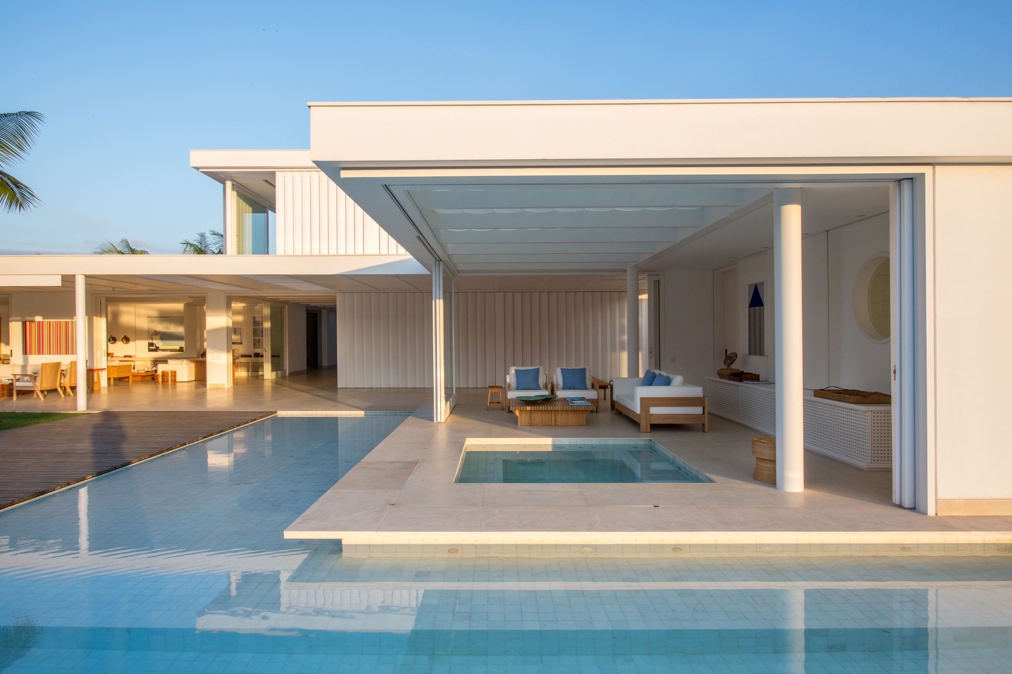 Covered terrace with integrated pool opening to the main deck at dusk under clear sky