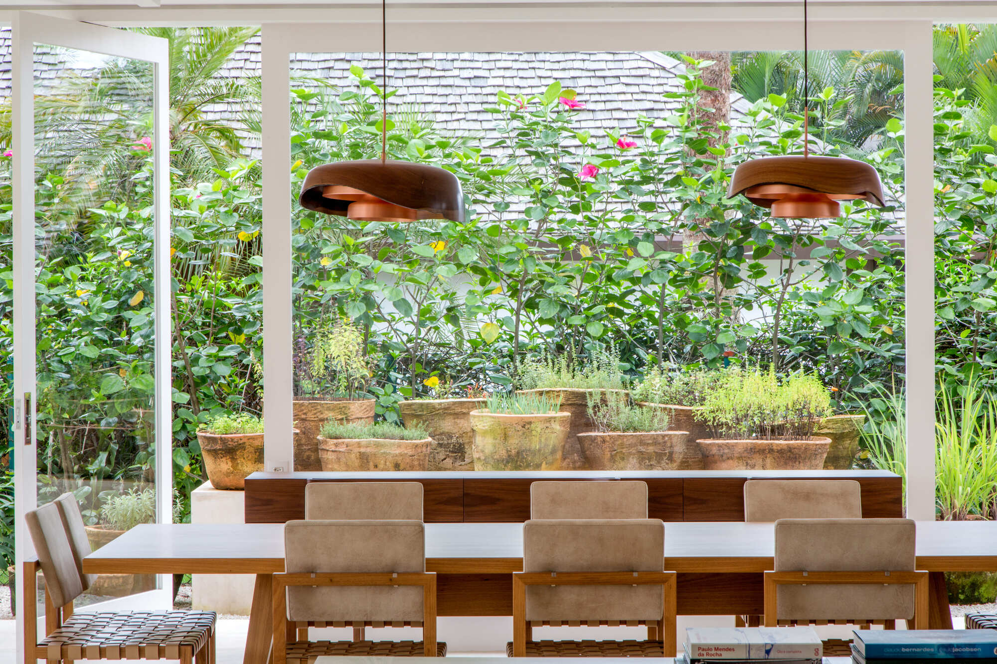 Dining area with timber table and pendant lights overlooking terraced planter beds and garden wall