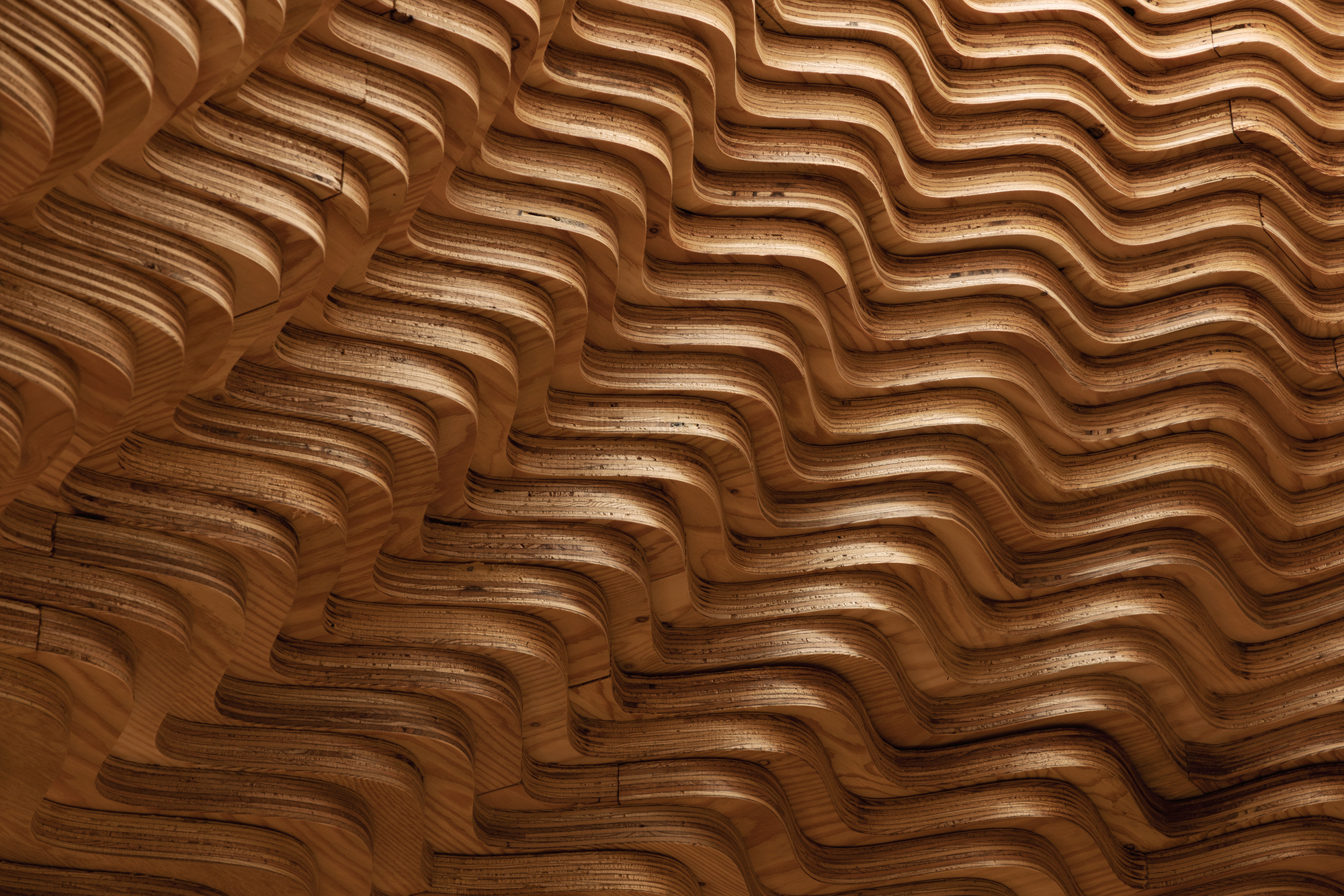 Close-up of the undulating laminated wood surface showing shadow and grain