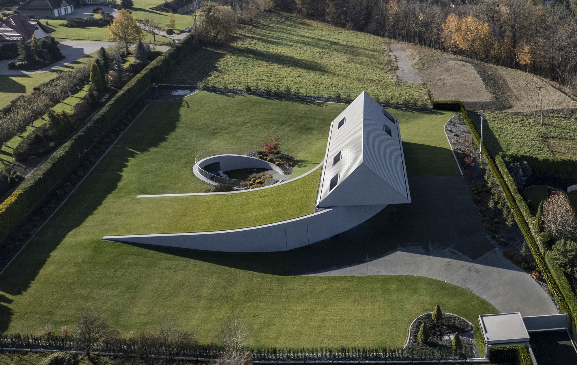 Aerial view of the white gabled volume with curved wing walls extending into the lawn