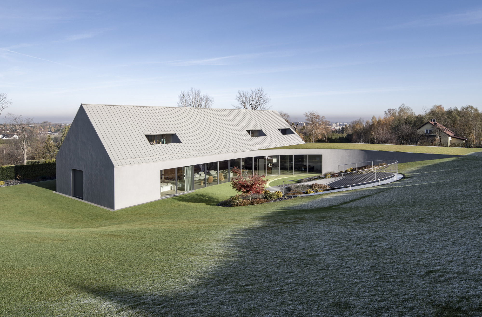 Garden facade with continuous glazing below the sloped metal roof on a frosty morning