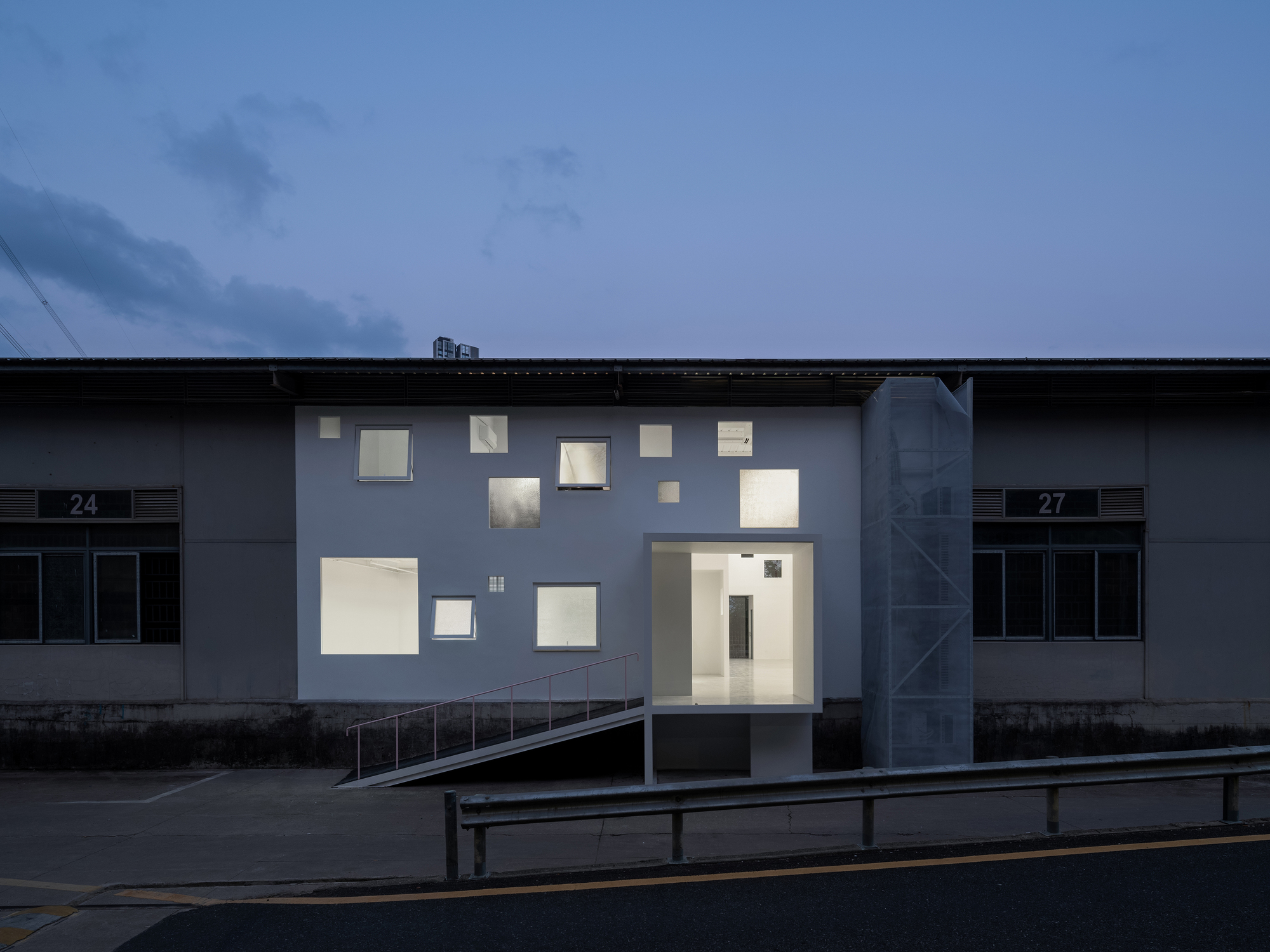 Front elevation showing irregular window openings illuminated against a dark blue evening sky