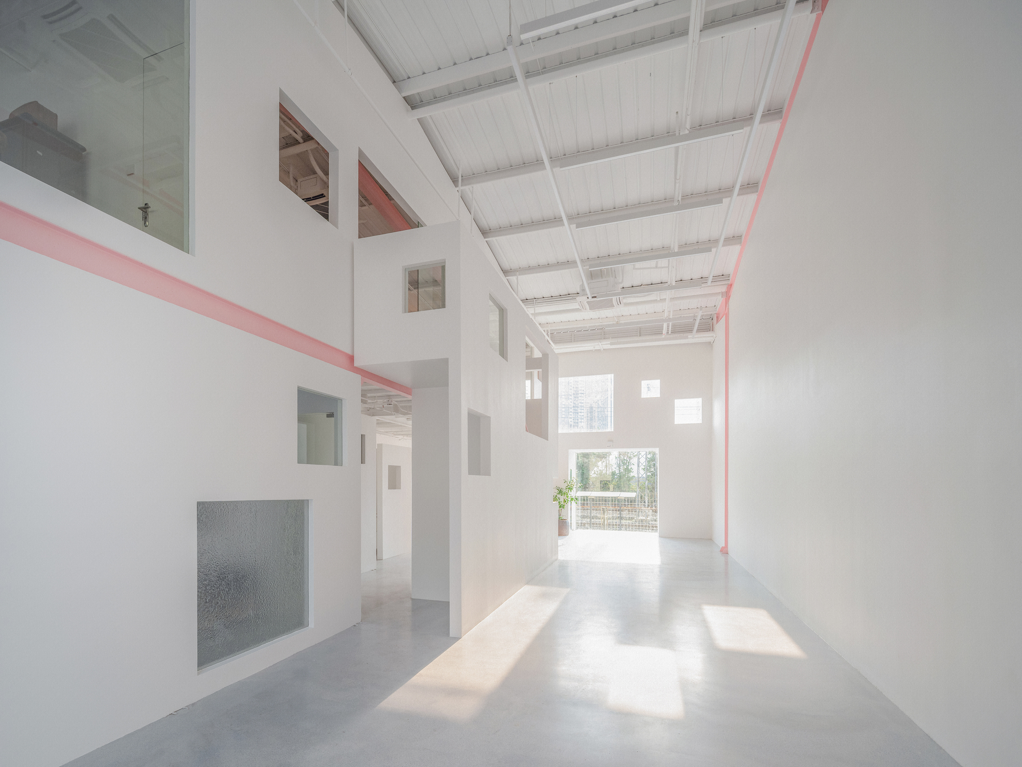Double-height interior hall with white walls, exposed ceiling joists and pink steel beams