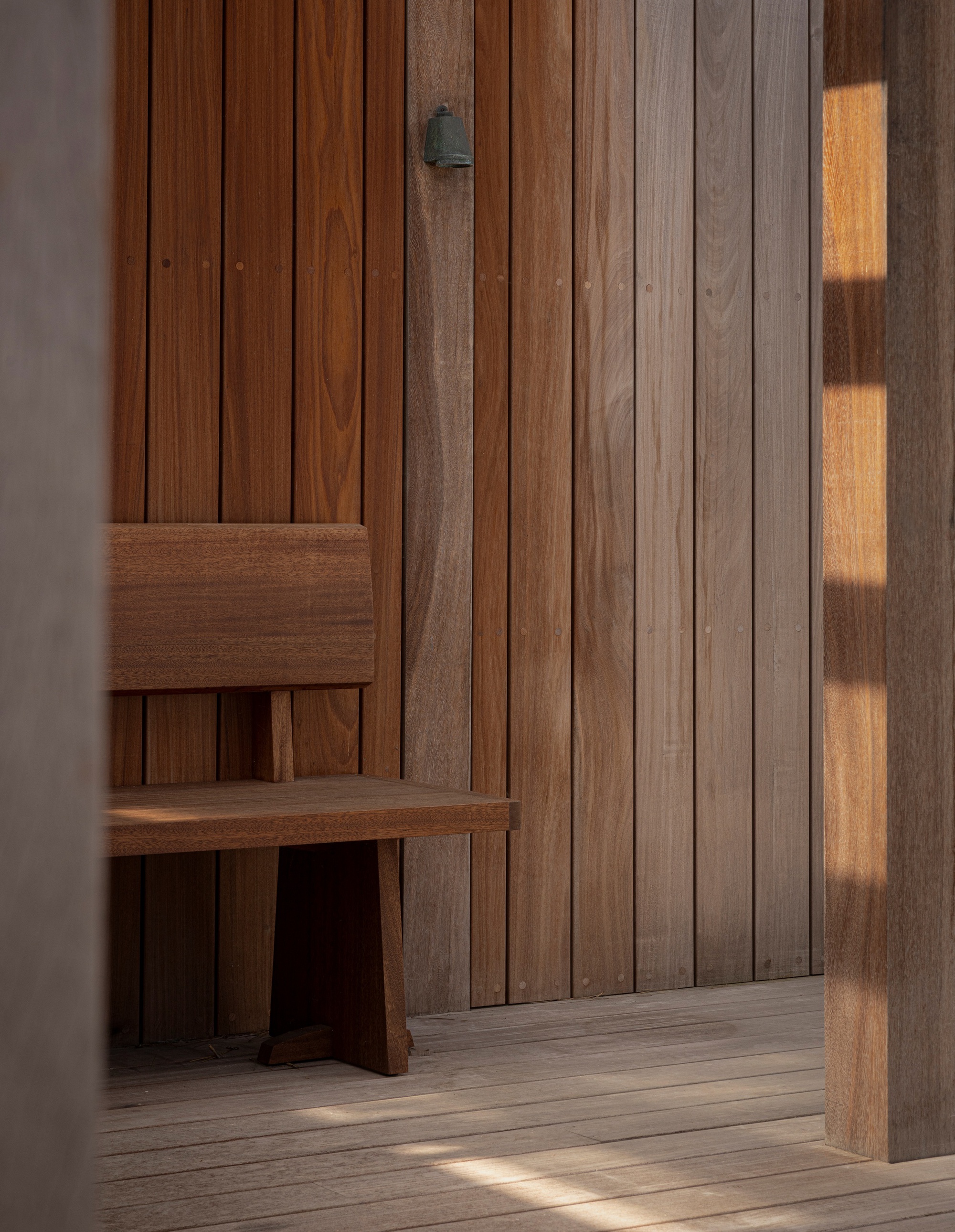 Interior timber wall cladding with a built-in bench illuminated by late afternoon sunlight