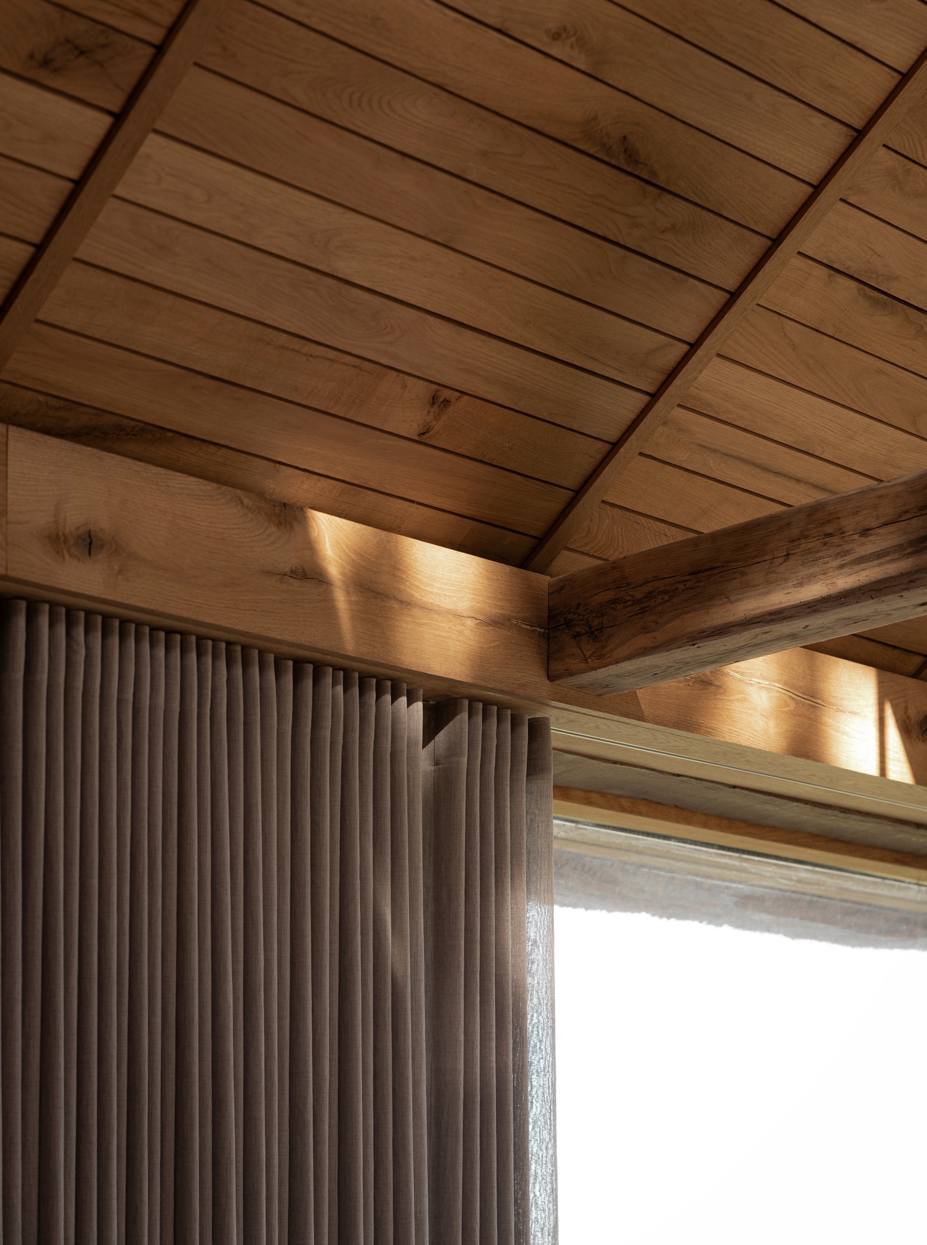 Interior corner showing timber ceiling beams and vertical fluted wall cladding with natural light