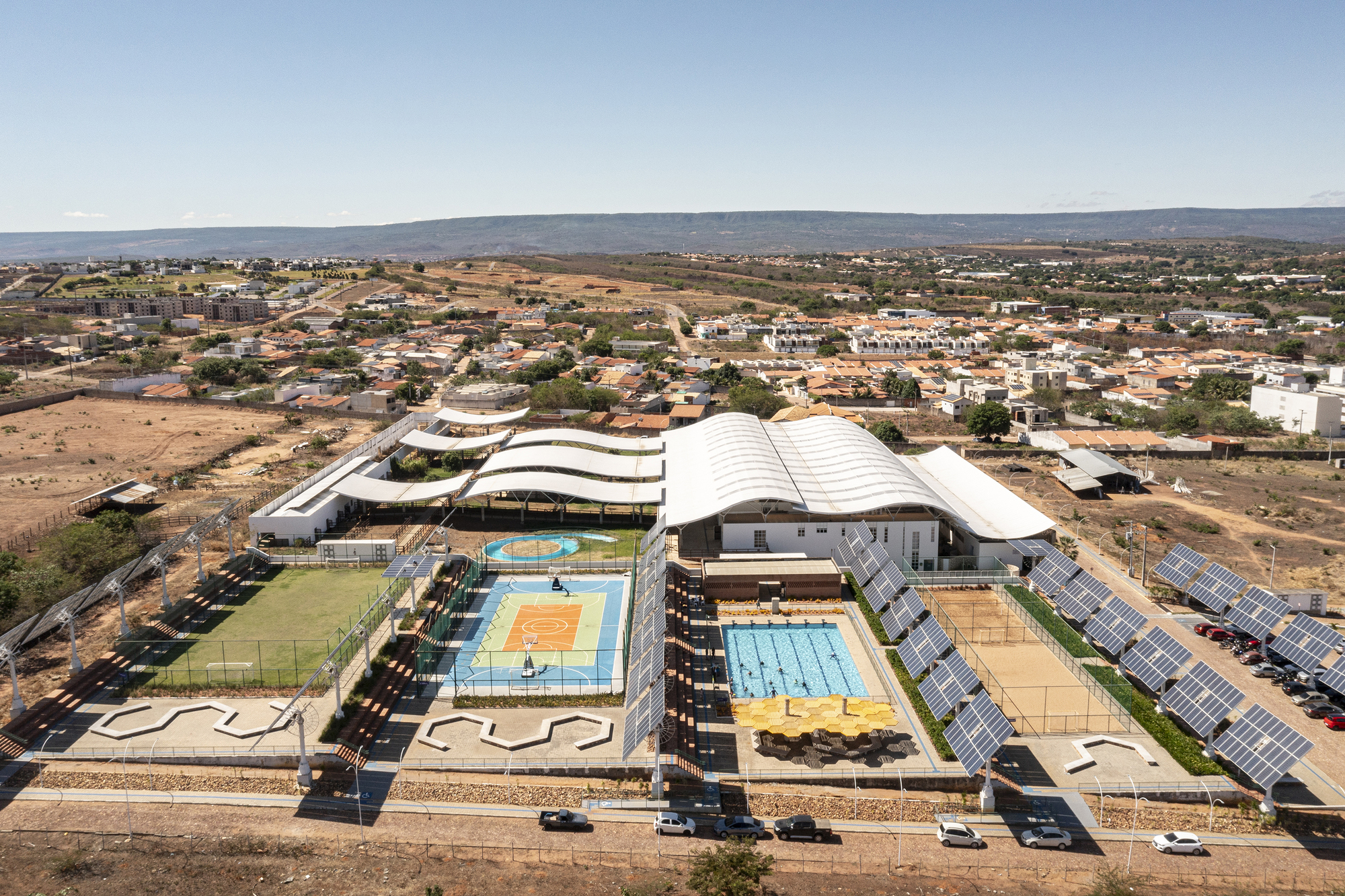 Aerial view of the sports complex with curved roofs and solar panel arrays in the arid landscape