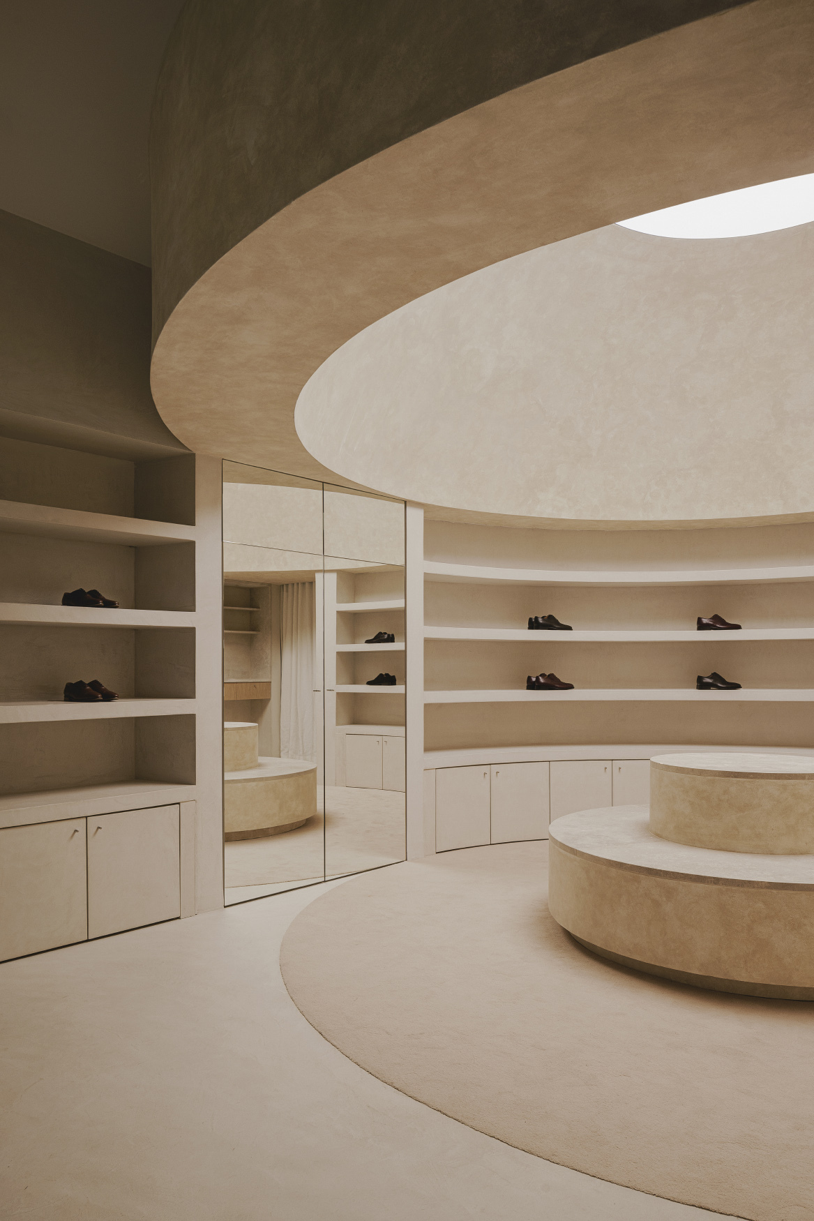 Curved shelving wall with mirror-fronted storage cabinet reflecting the circular display platform