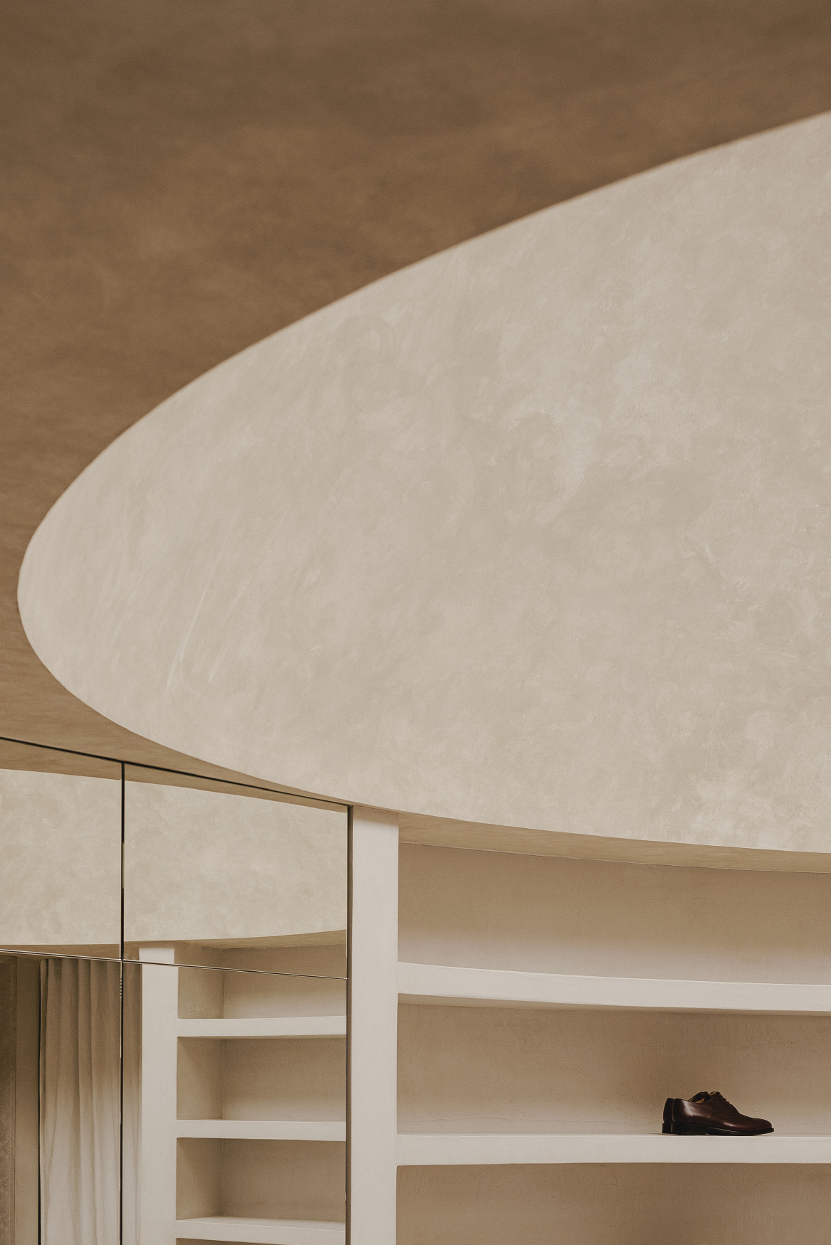 Interior view of pale plaster ceiling vault meeting timber shelving and glass partition