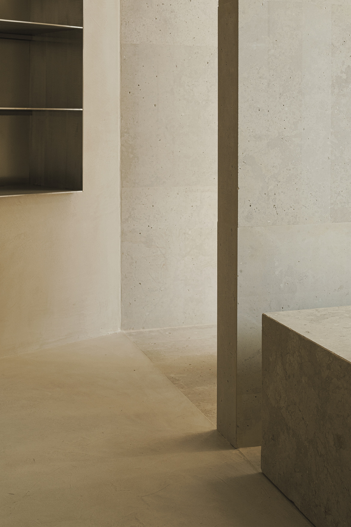 Concrete column and plinth corner beneath board-formed concrete walls and concealed ceiling lighting