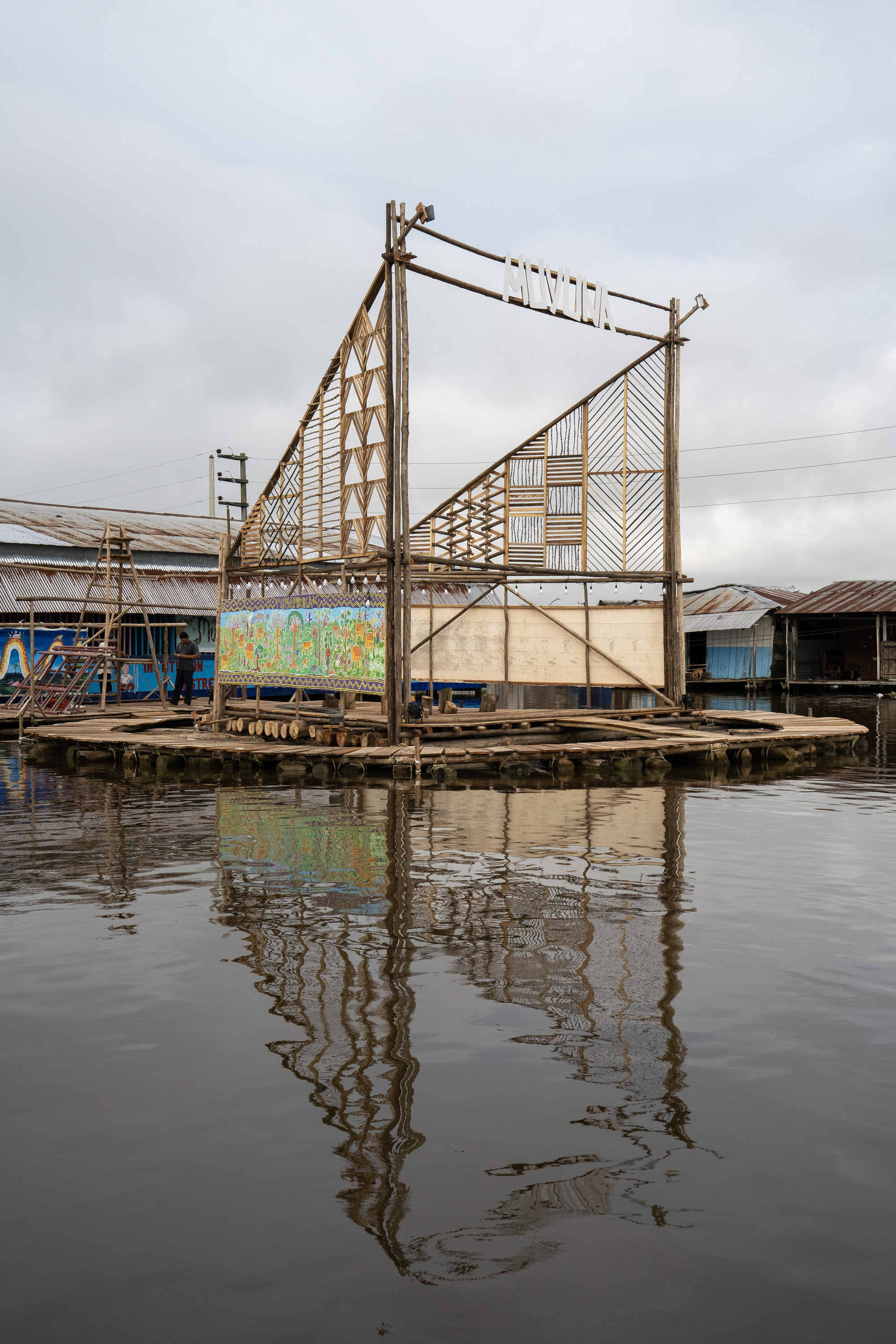 Floating bamboo and timber stage platform with geometric panels reflected in still water
