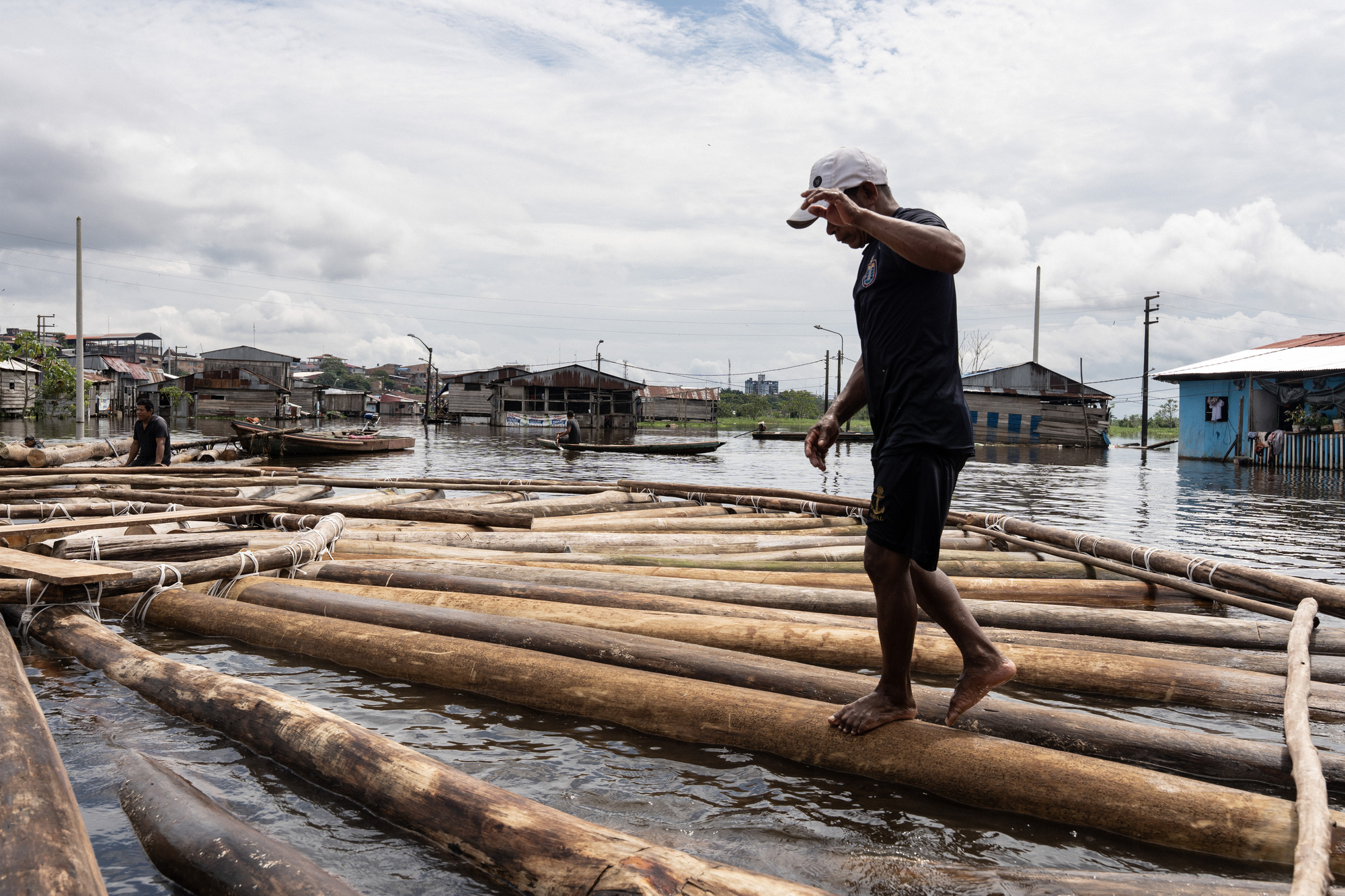 Person walking across a floating platform made of lashed timber logs during an overcast day