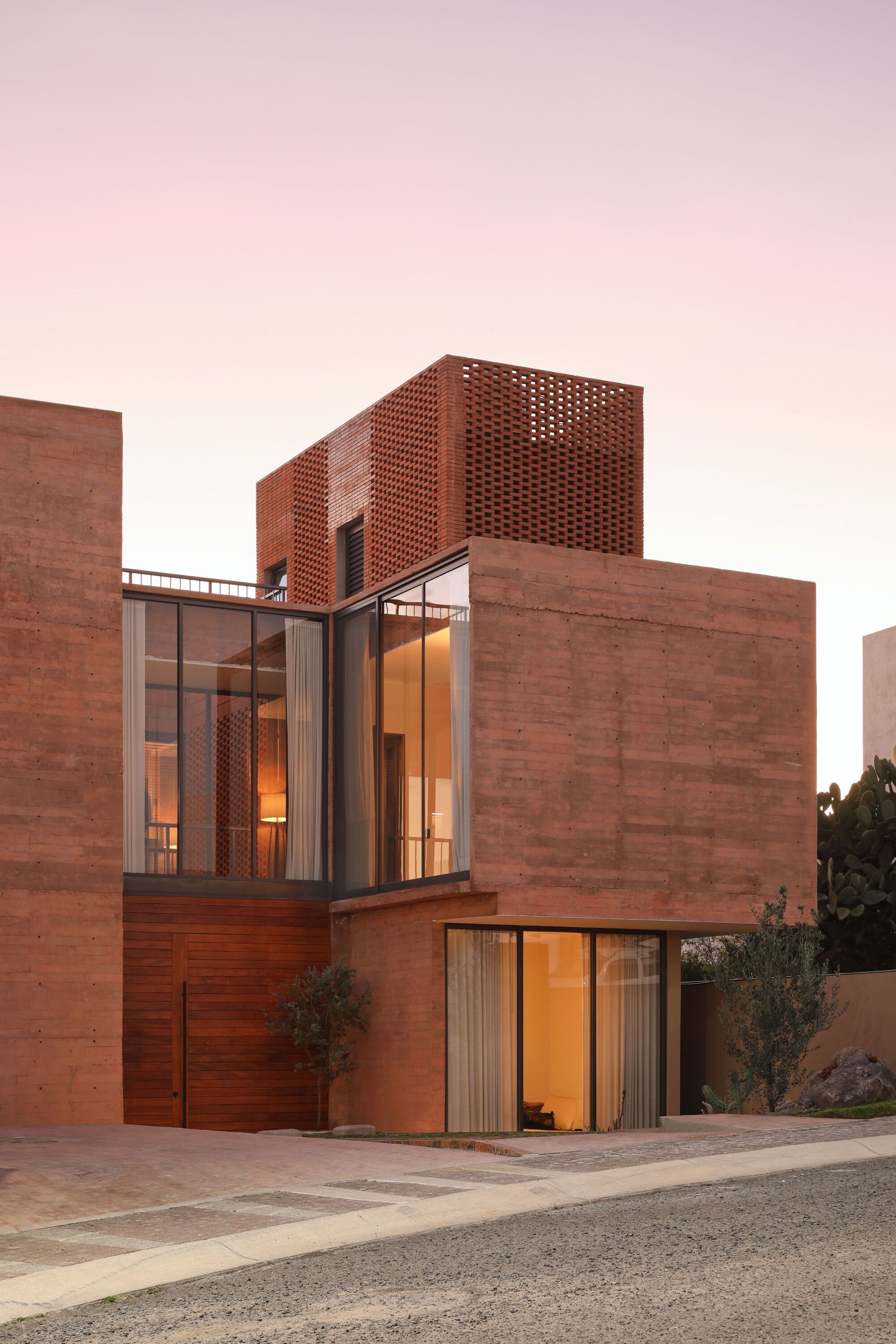 Street-facing elevation showing perforated brick screen above glass-walled living space with timber cladding at ground level