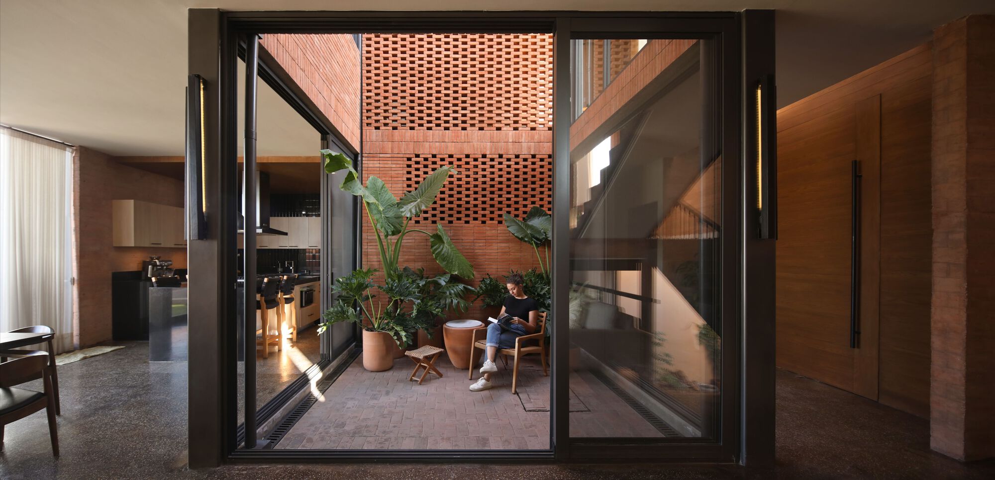 Interior courtyard with perforated brick screen wall, potted palms and resident reading in afternoon light