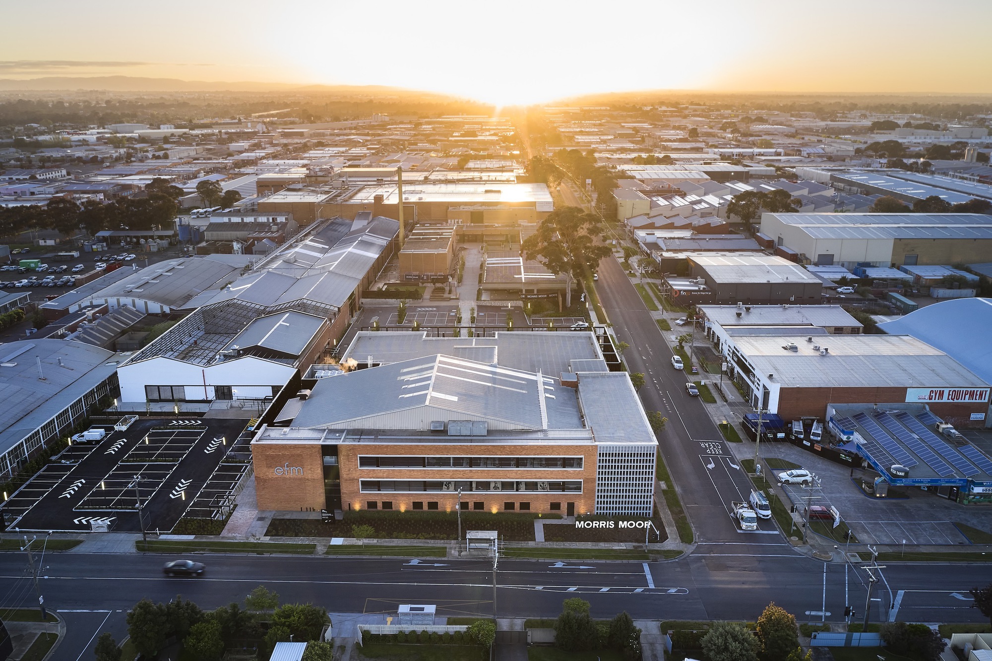 Aerial view of the timber and perforated metal facade among warehouses at sunset