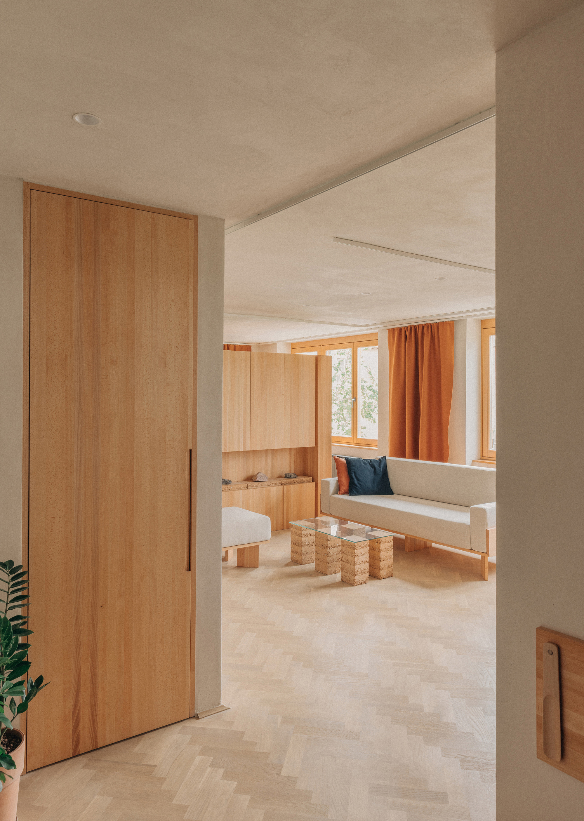 Timber door opening to a living room with built-in seating nook and woven side tables